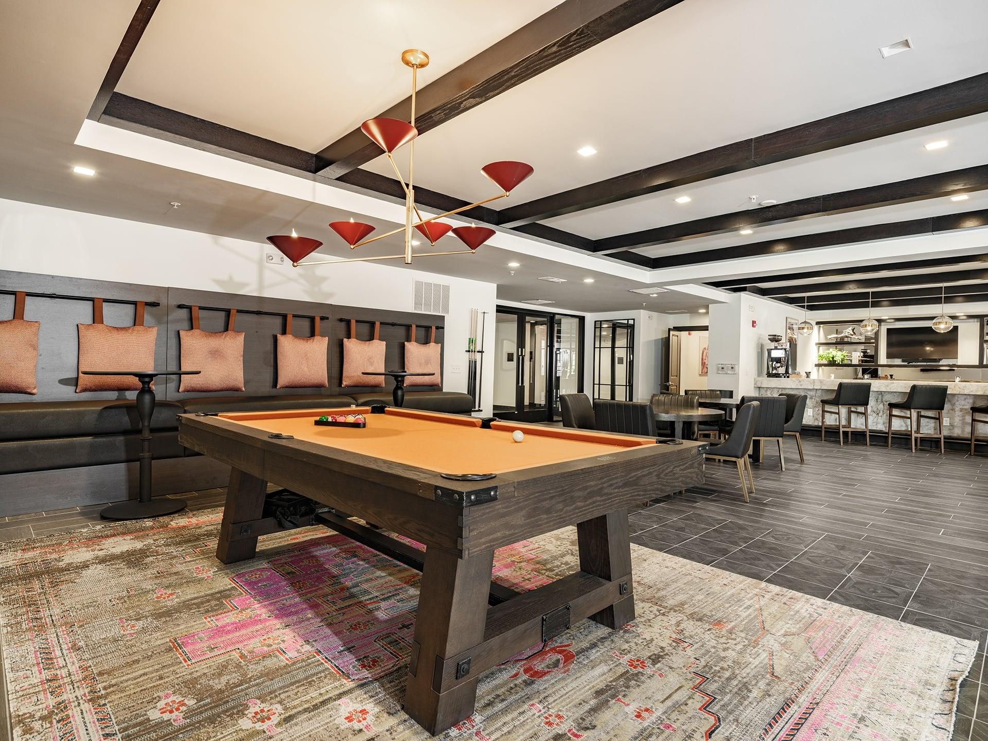 A pool table in a room with a high ceiling and a rug on the floor.