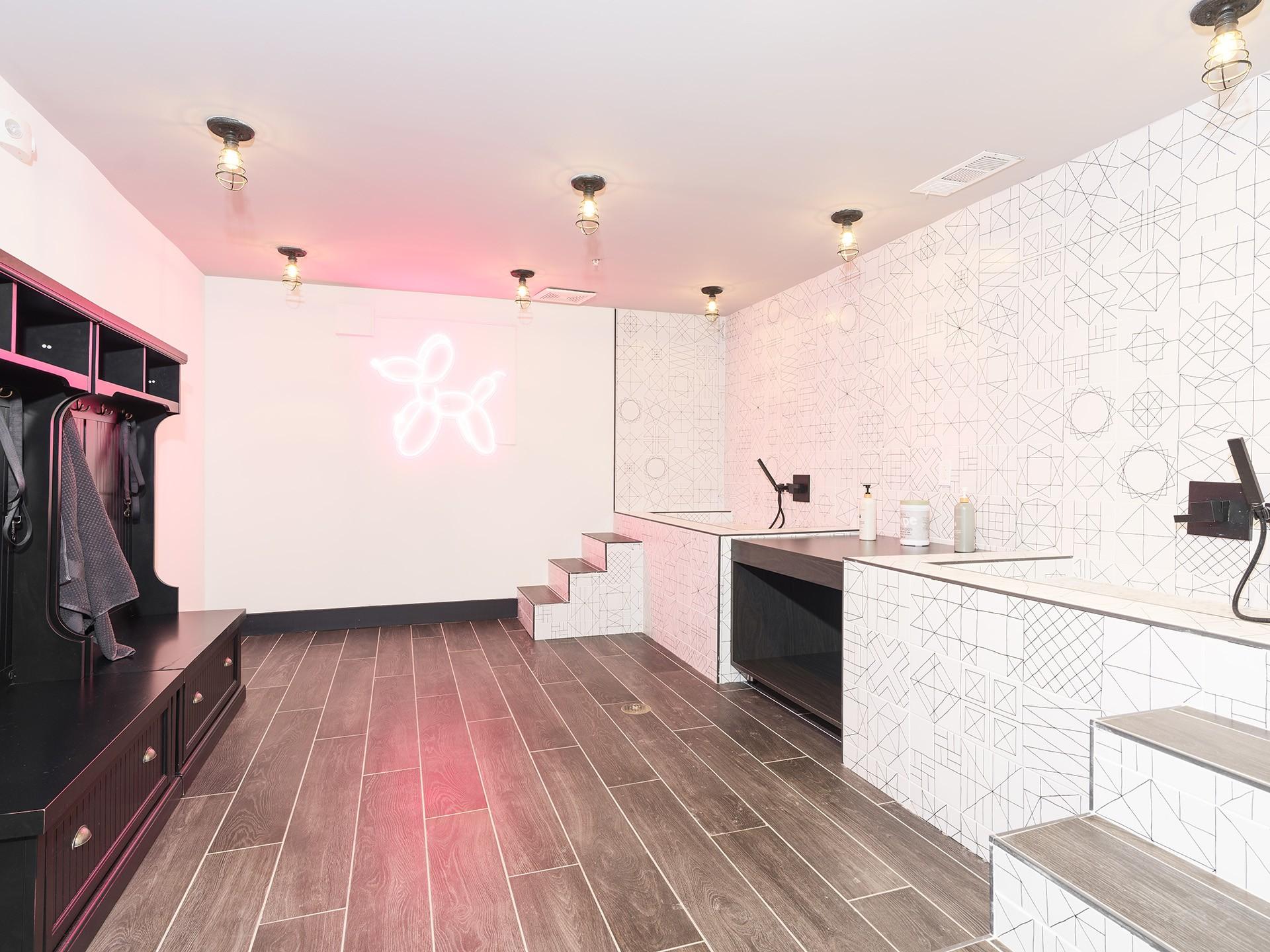 A bathroom with a pink neon sign on the wall.