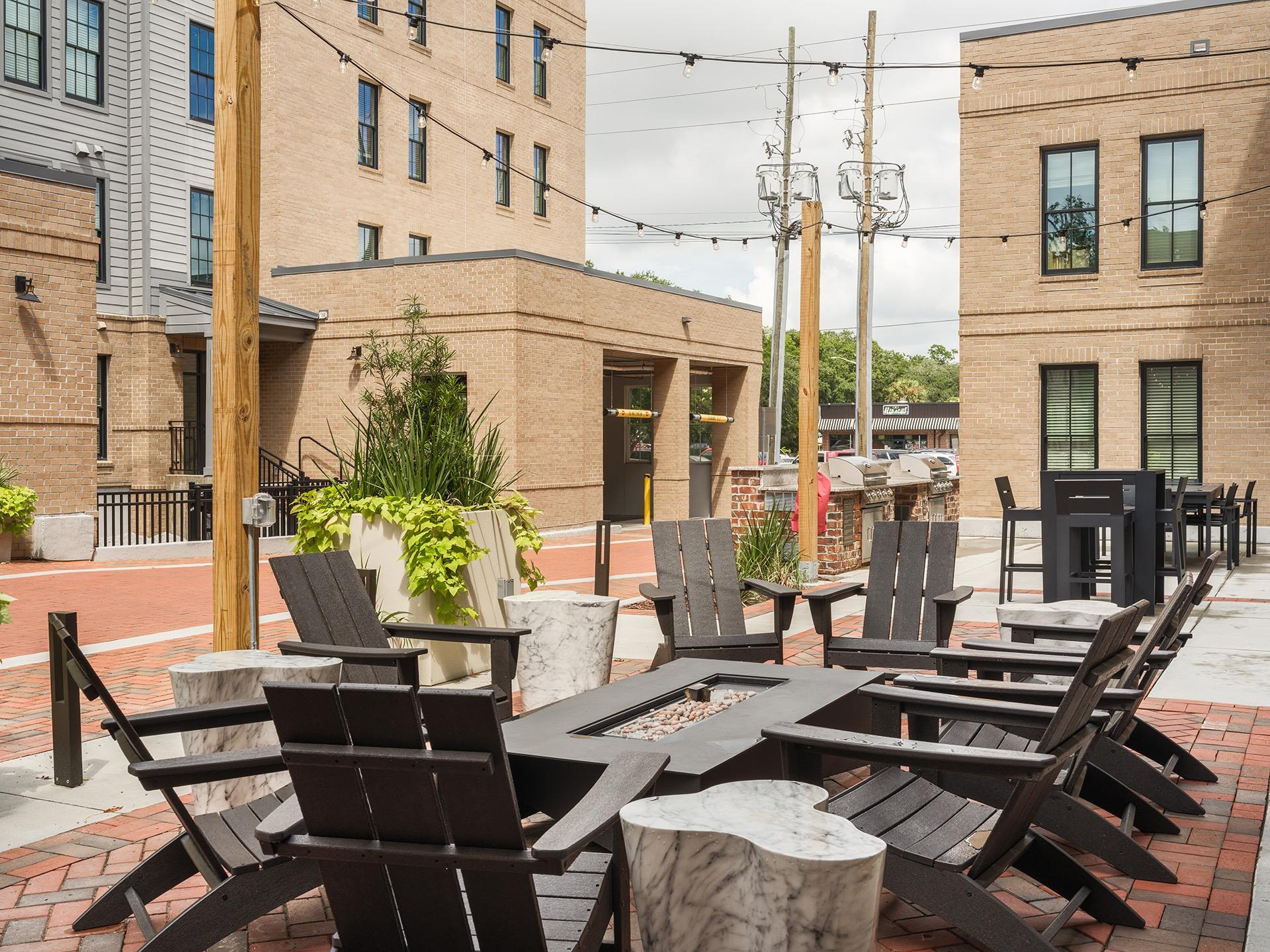 A row of black chairs are lined up on a brick patio.