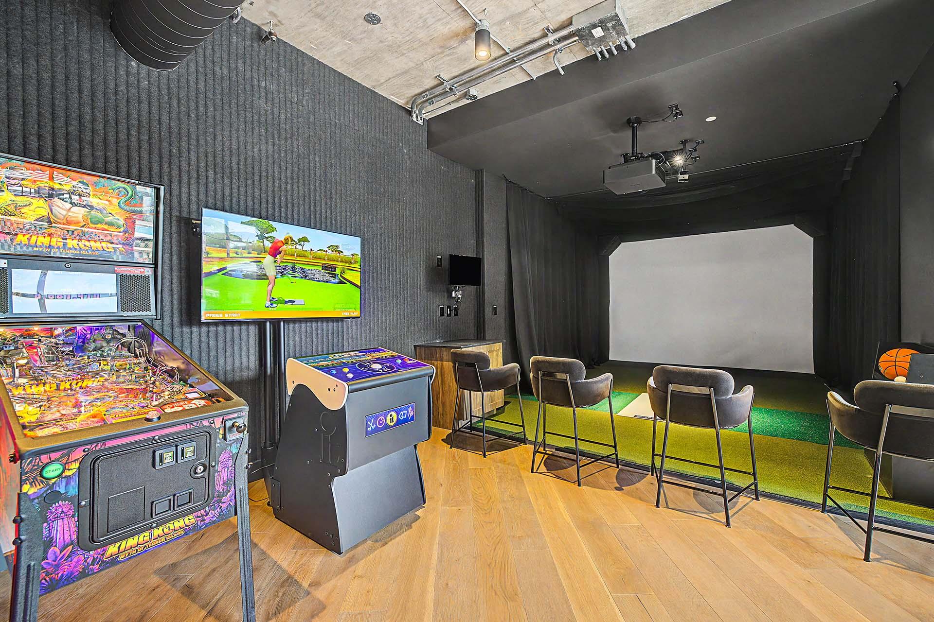 A room with a pinball machine, a projector, and chairs.
