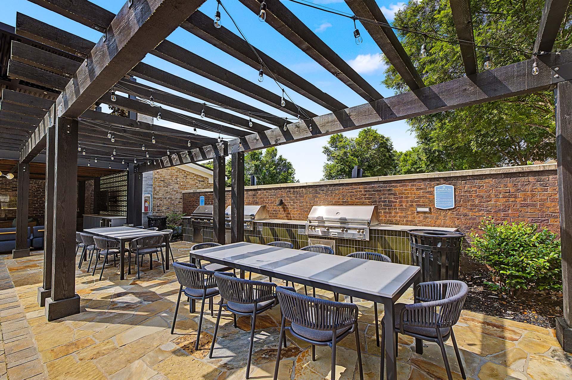 A patio with tables and chairs under a wooden pergola.