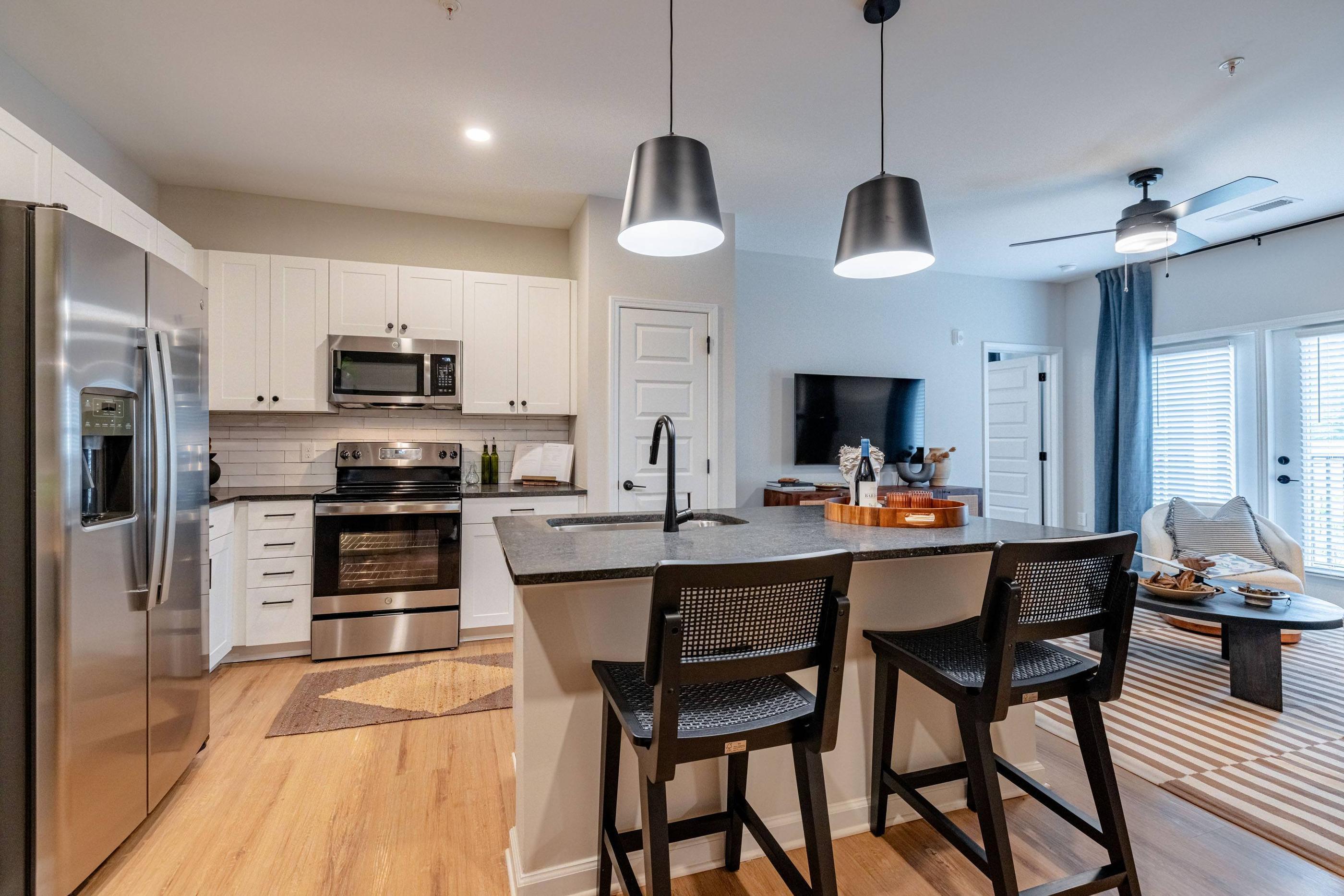 A modern kitchen with a refrigerator, microwave, oven, and sink.
