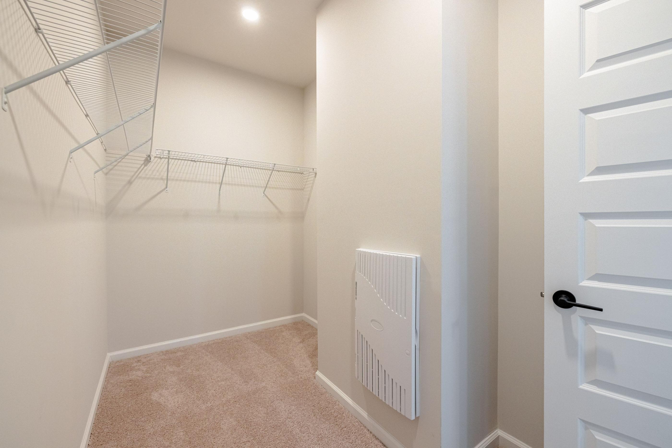 A white closet with a white door and a white radiator on the wall.