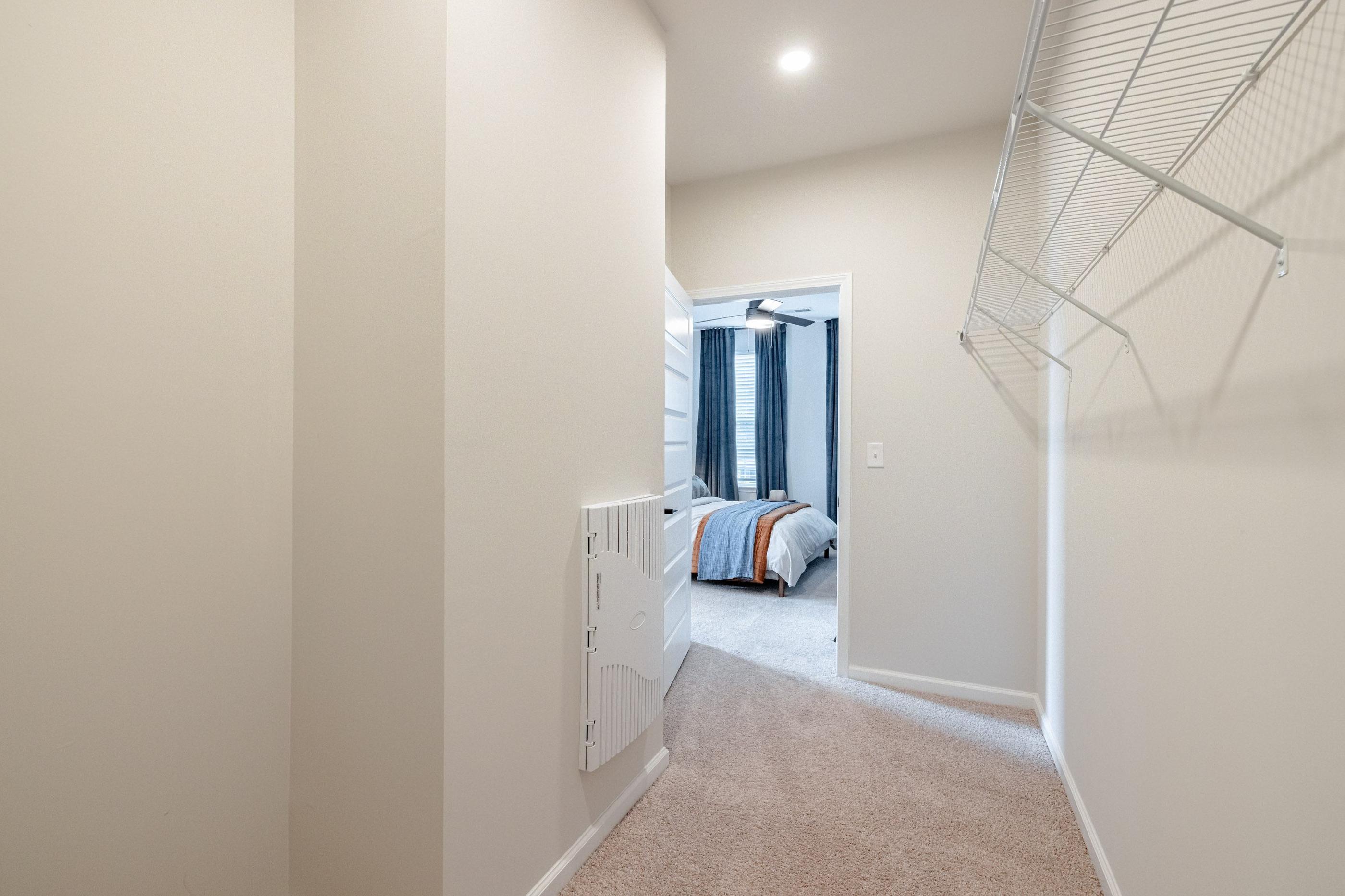 A room with a carpeted floor and a bed with a blue and orange blanket.