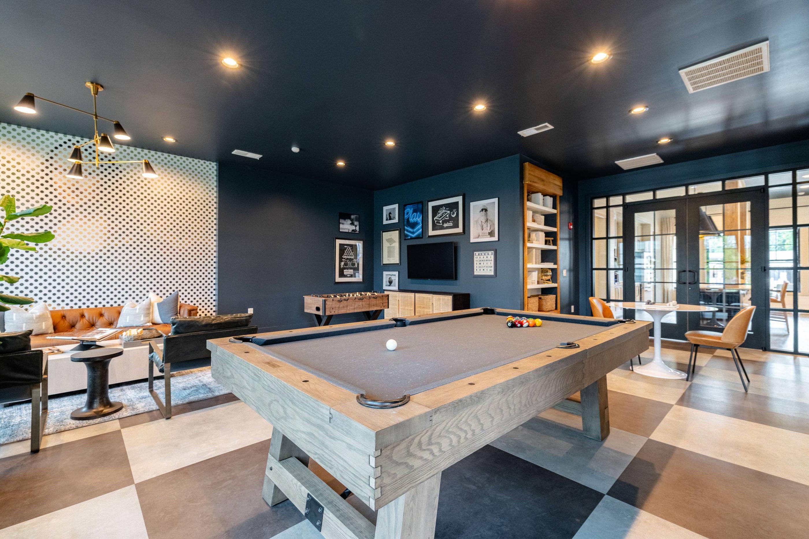 A pool table in a room with a dark wall and a light-colored floor.