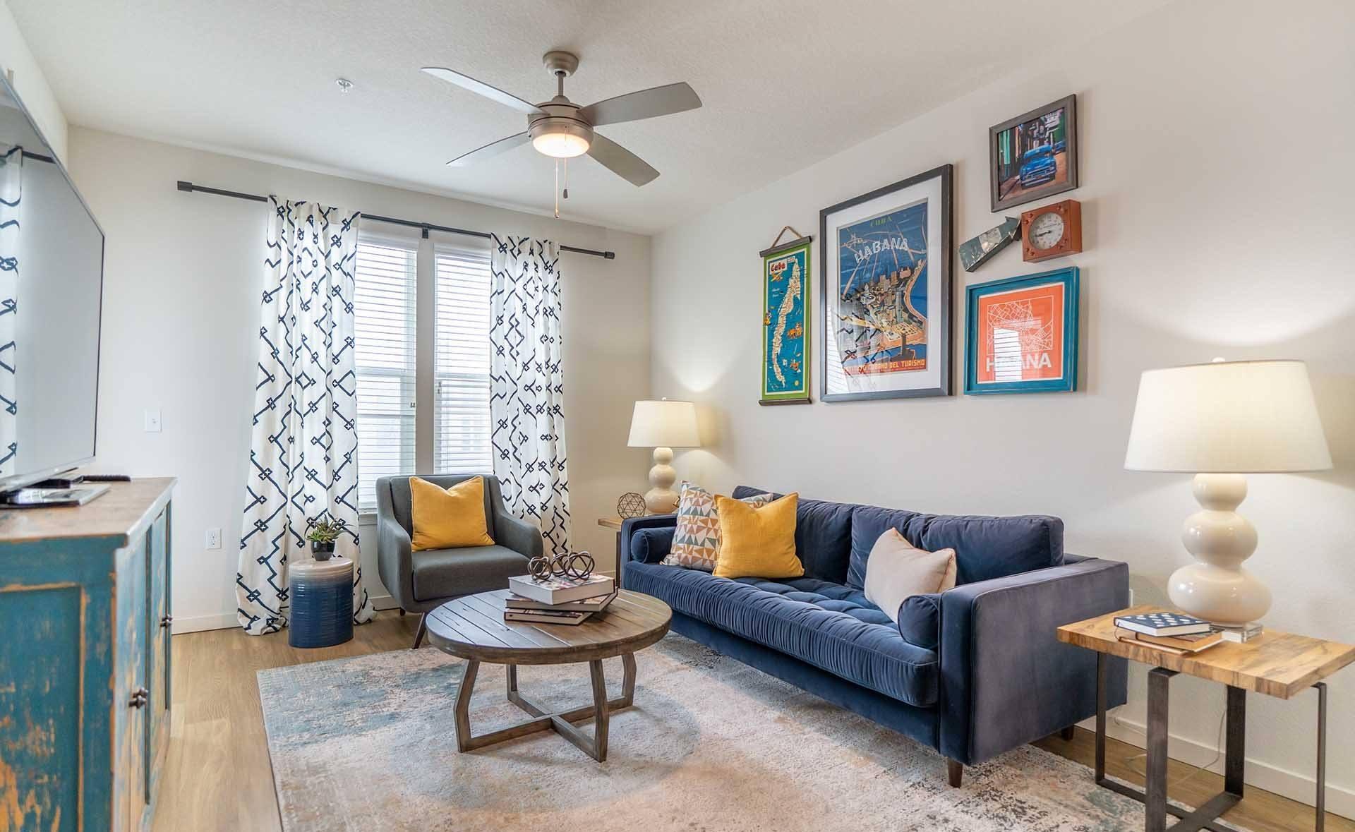 A living room with a blue couch, a coffee table, and a ceiling fan.