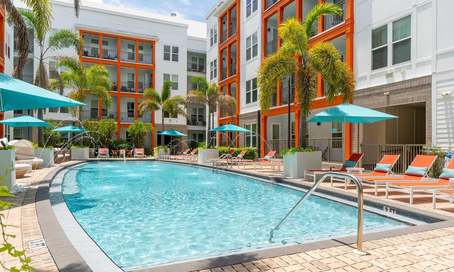 A pool surrounded by chairs and umbrellas.