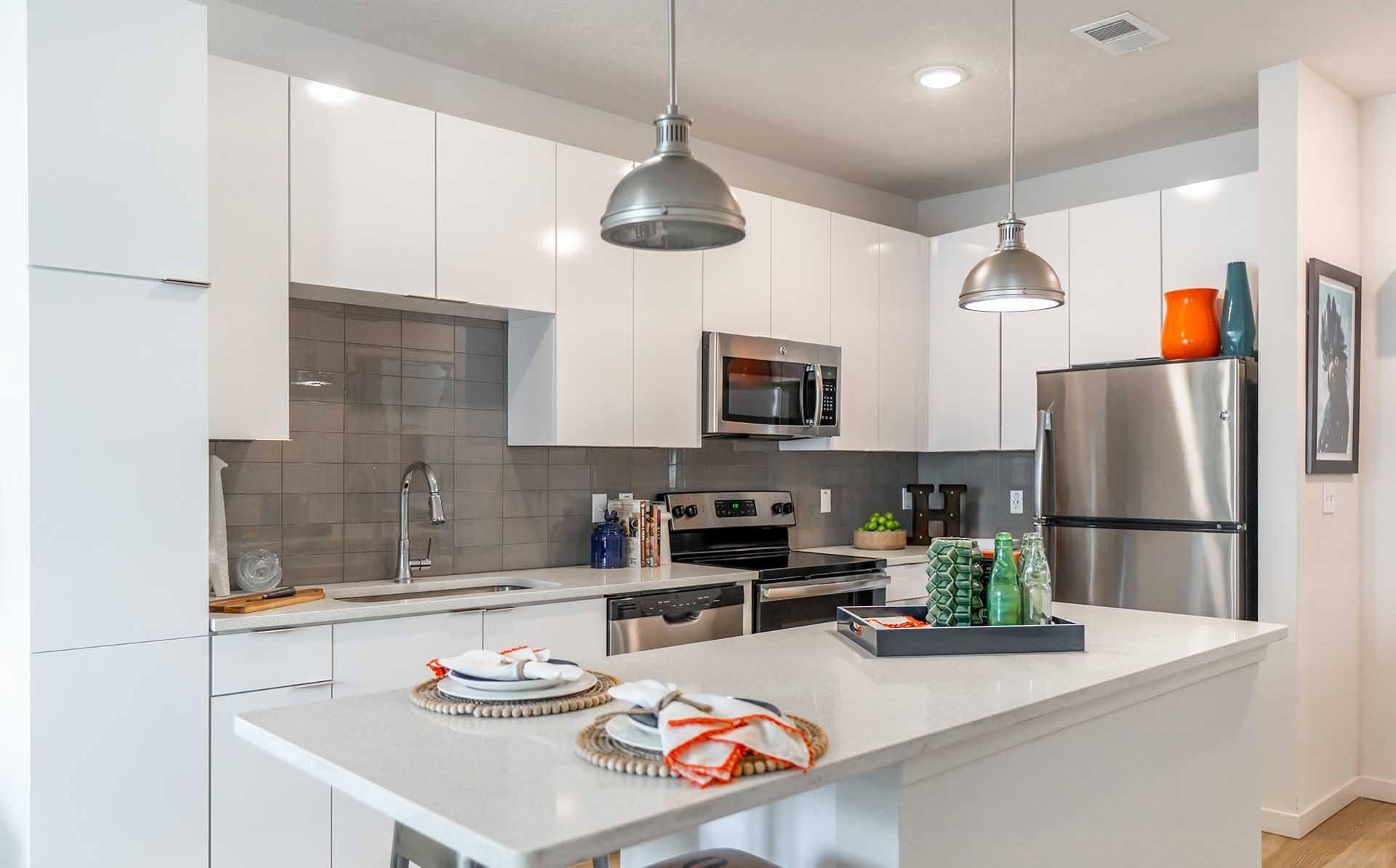 A modern kitchen with a white countertop and stainless steel appliances.