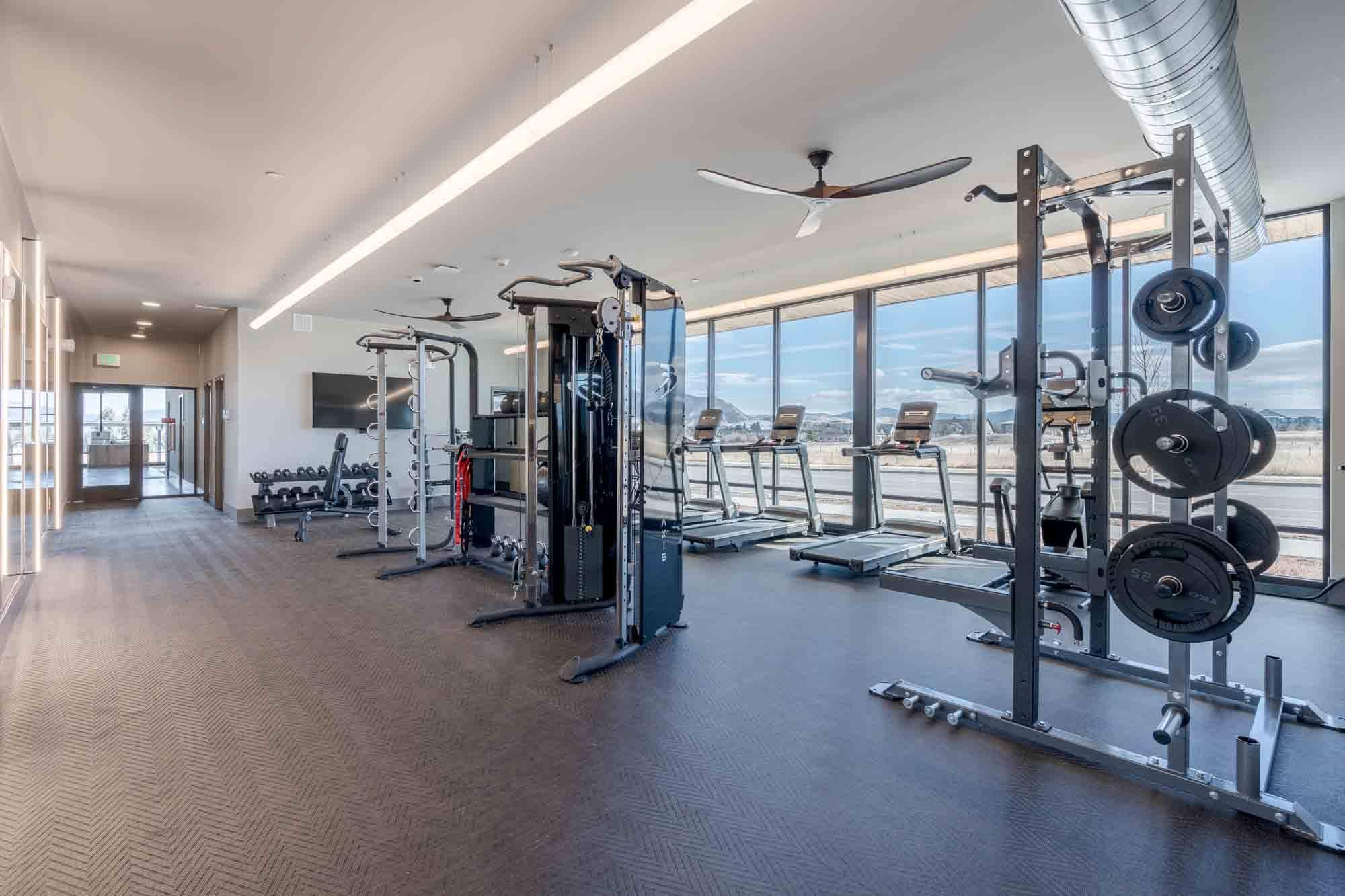 A spacious gym with a variety of equipment and a view of the outside.