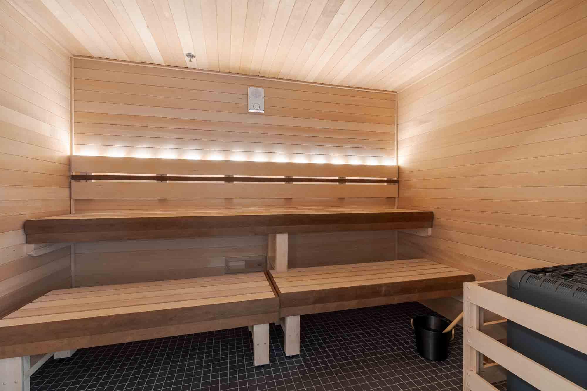 A wooden sauna with benches and lights on the wall.
