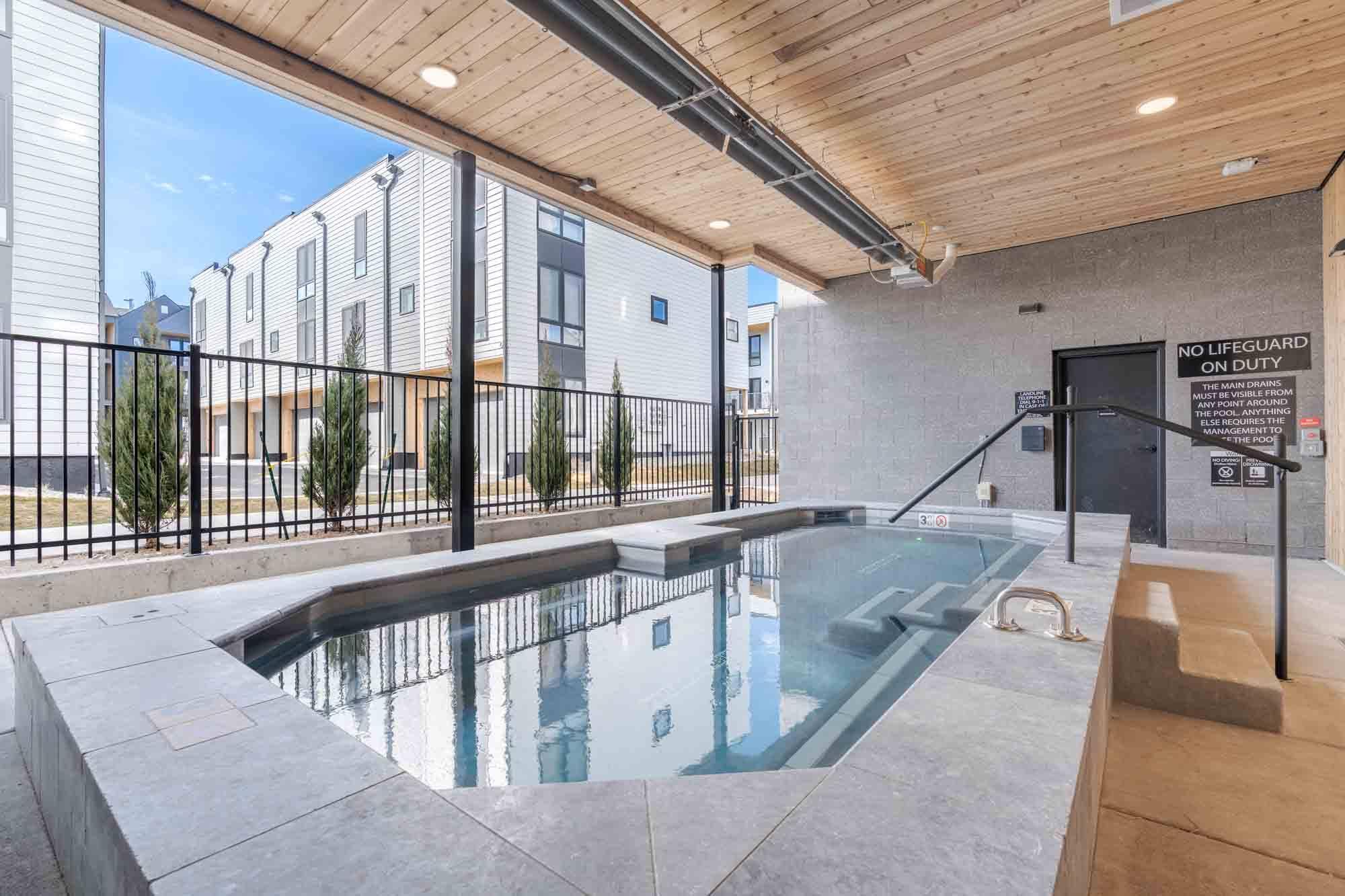A pool with a black fence and a sign that says no lifeguard on duty.