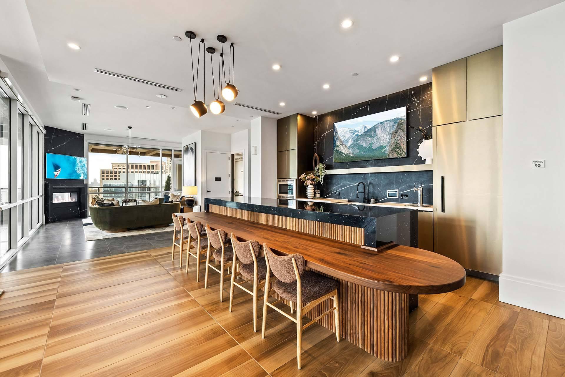 A modern kitchen with a long wooden island and chairs.