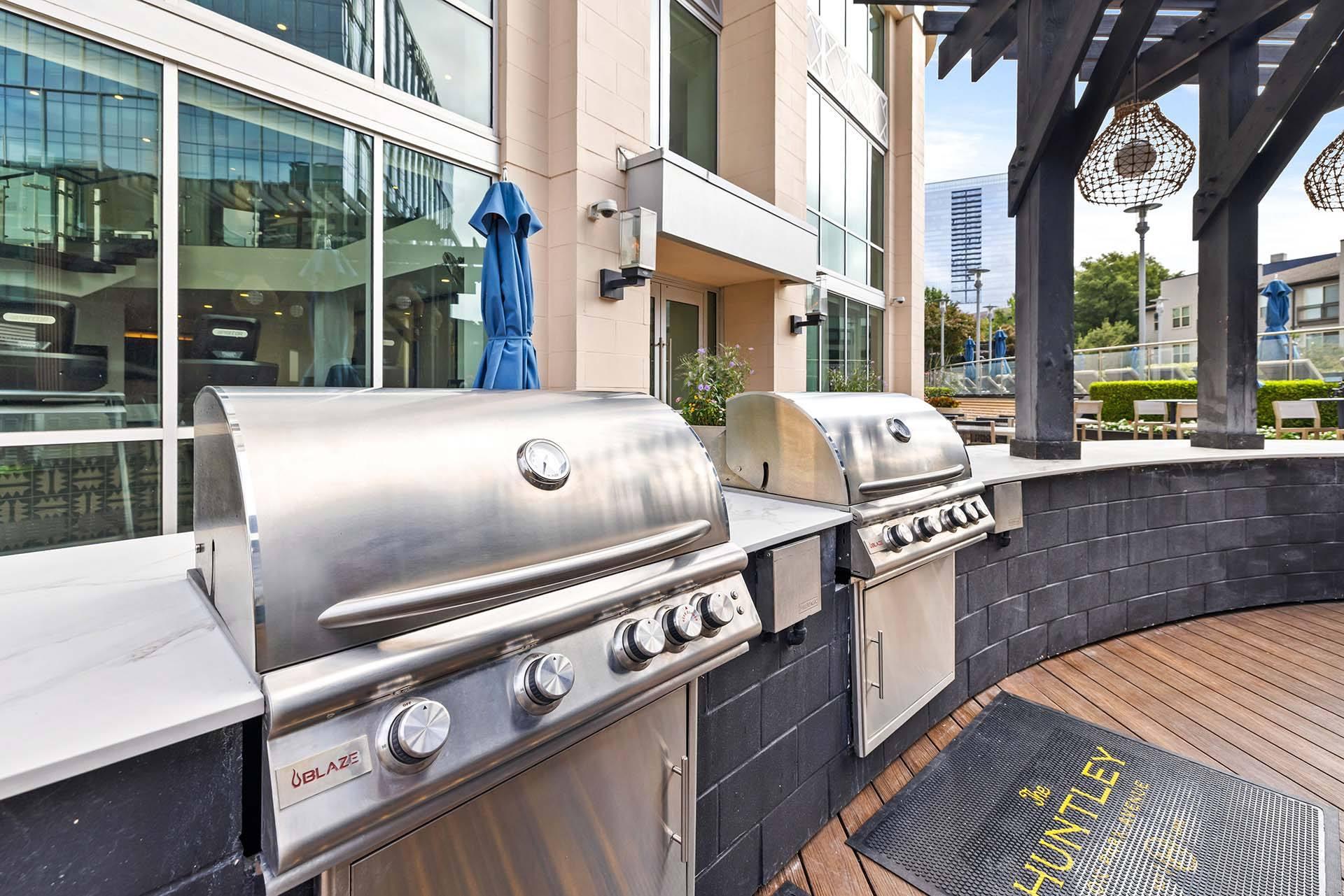A stainless steel outdoor grill is on a wooden deck.