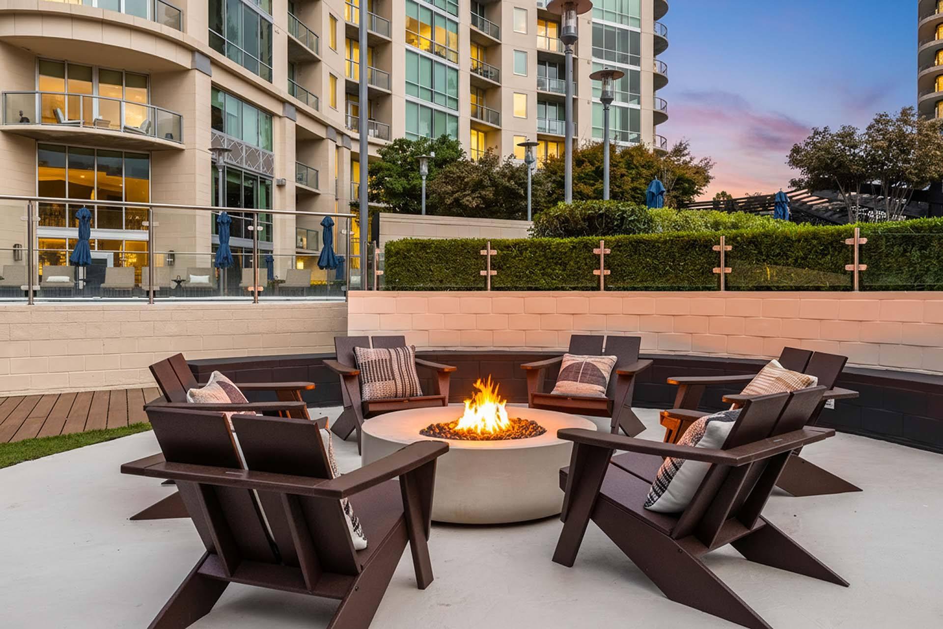 A fire pit sits in the middle of a patio surrounded by chairs.