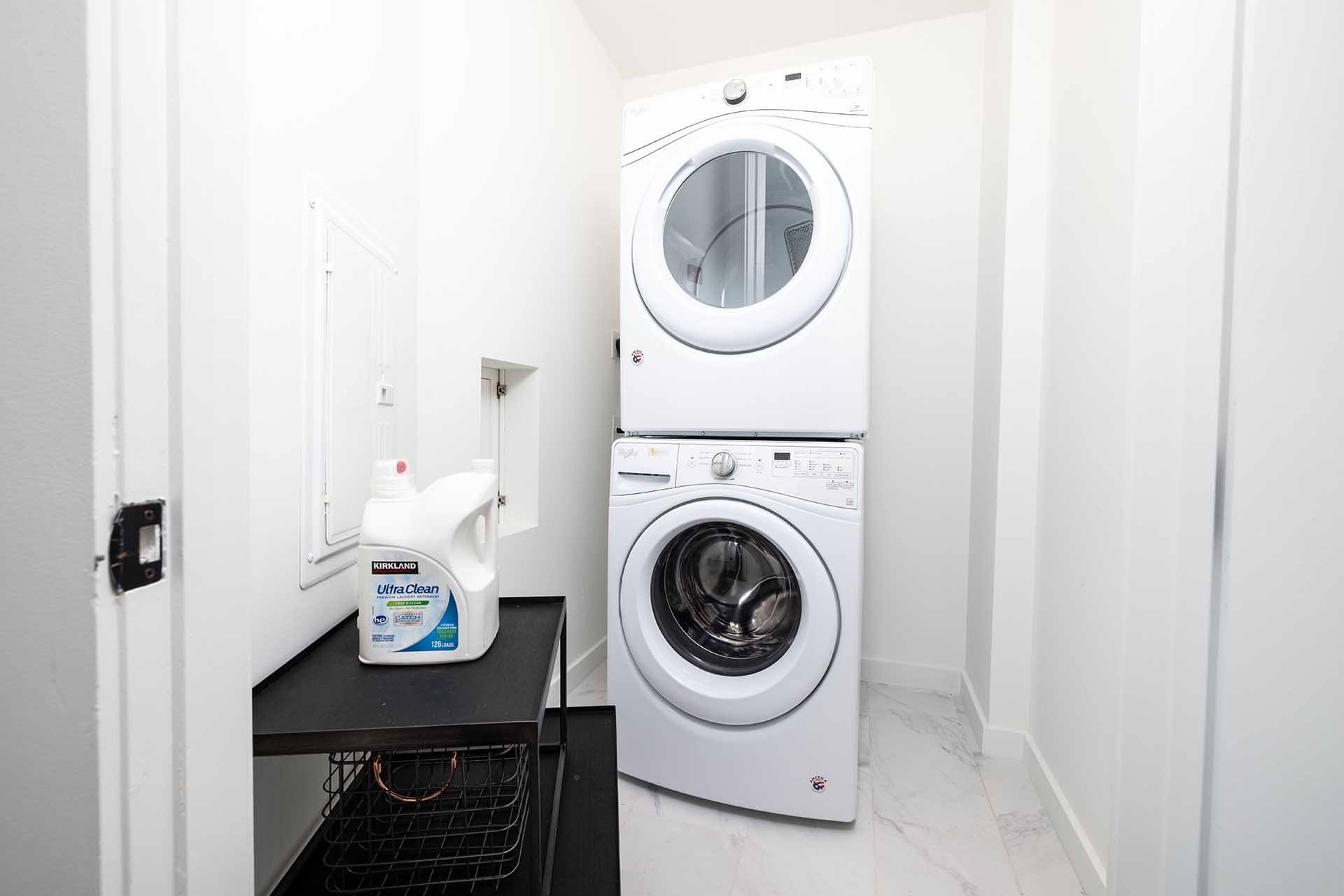 A white washing machine is in a small laundry room.