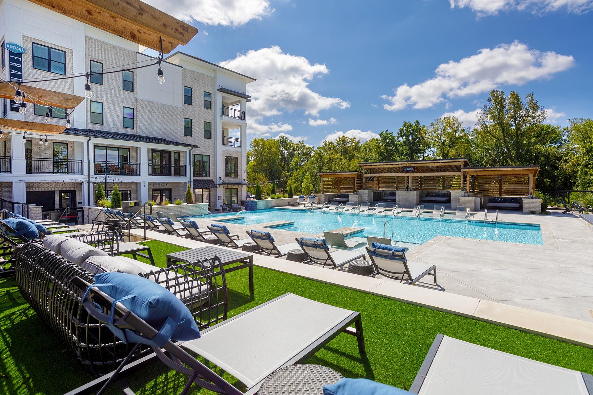 A large outdoor pool area with sun loungers and a building in the background.