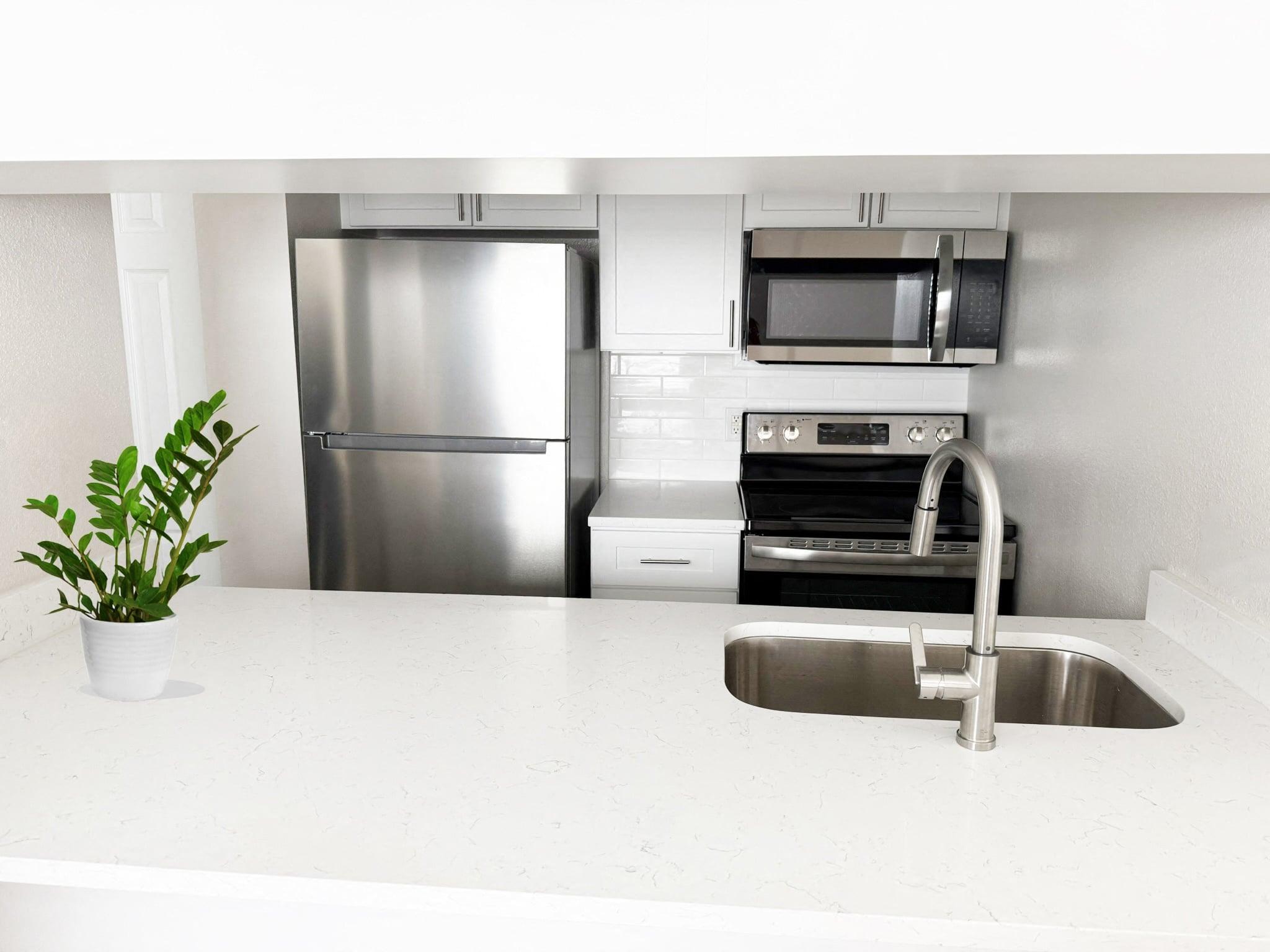 A kitchen with a stainless steel refrigerator, microwave, oven, and dishwasher.