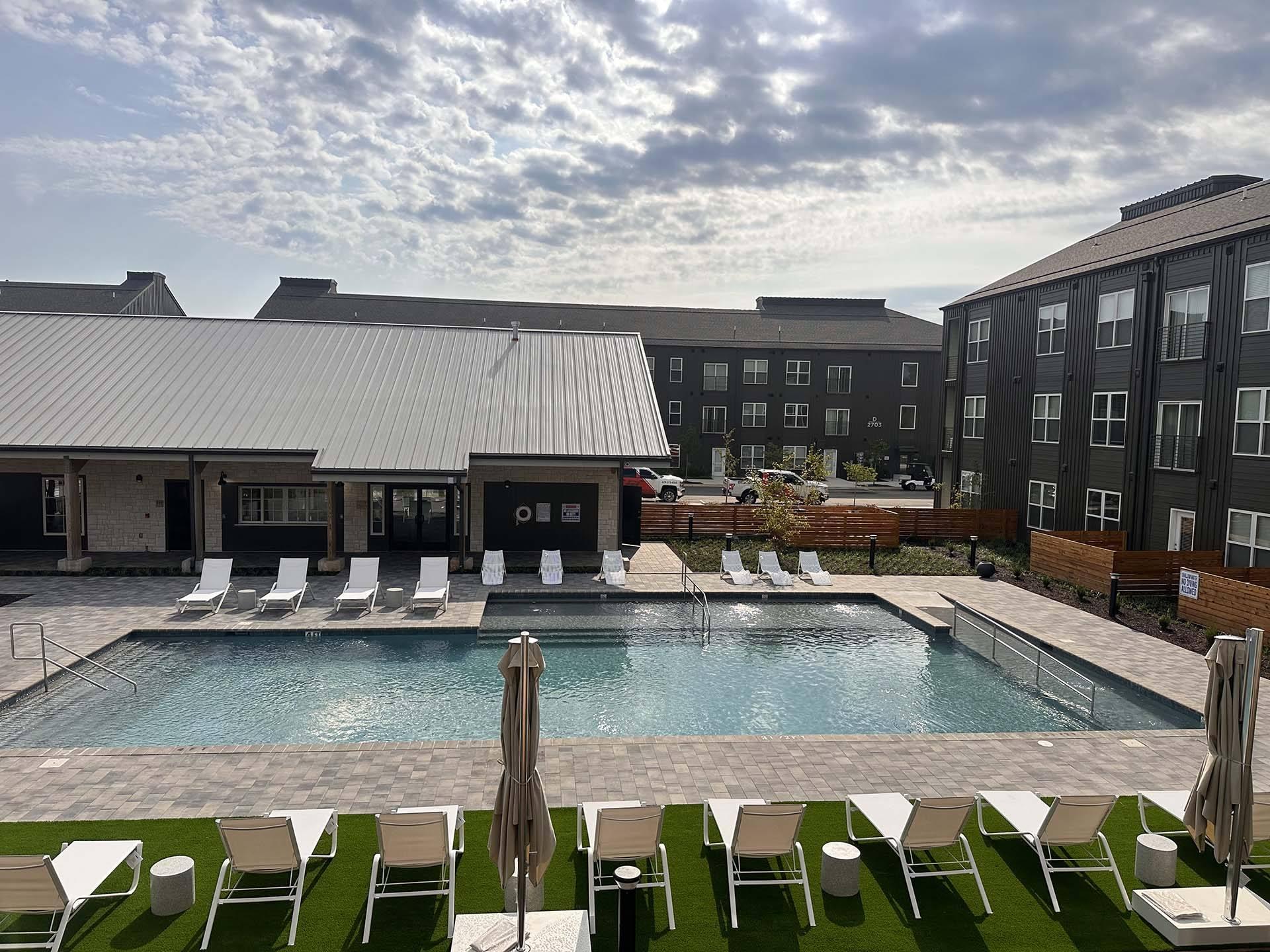 an outdoor pool with chairs and a building