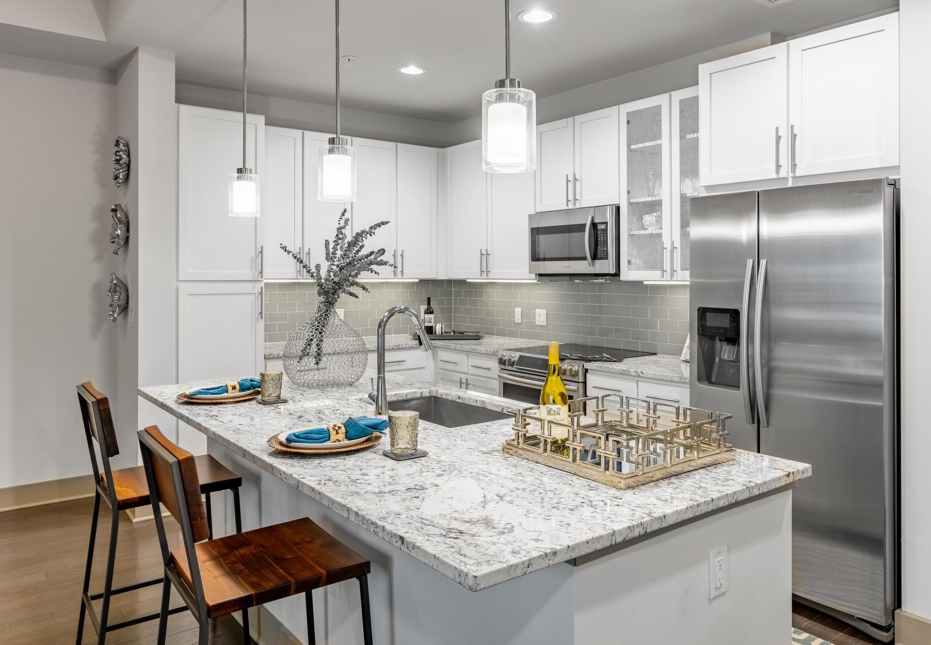 A modern kitchen with a marble countertop and stainless steel appliances.