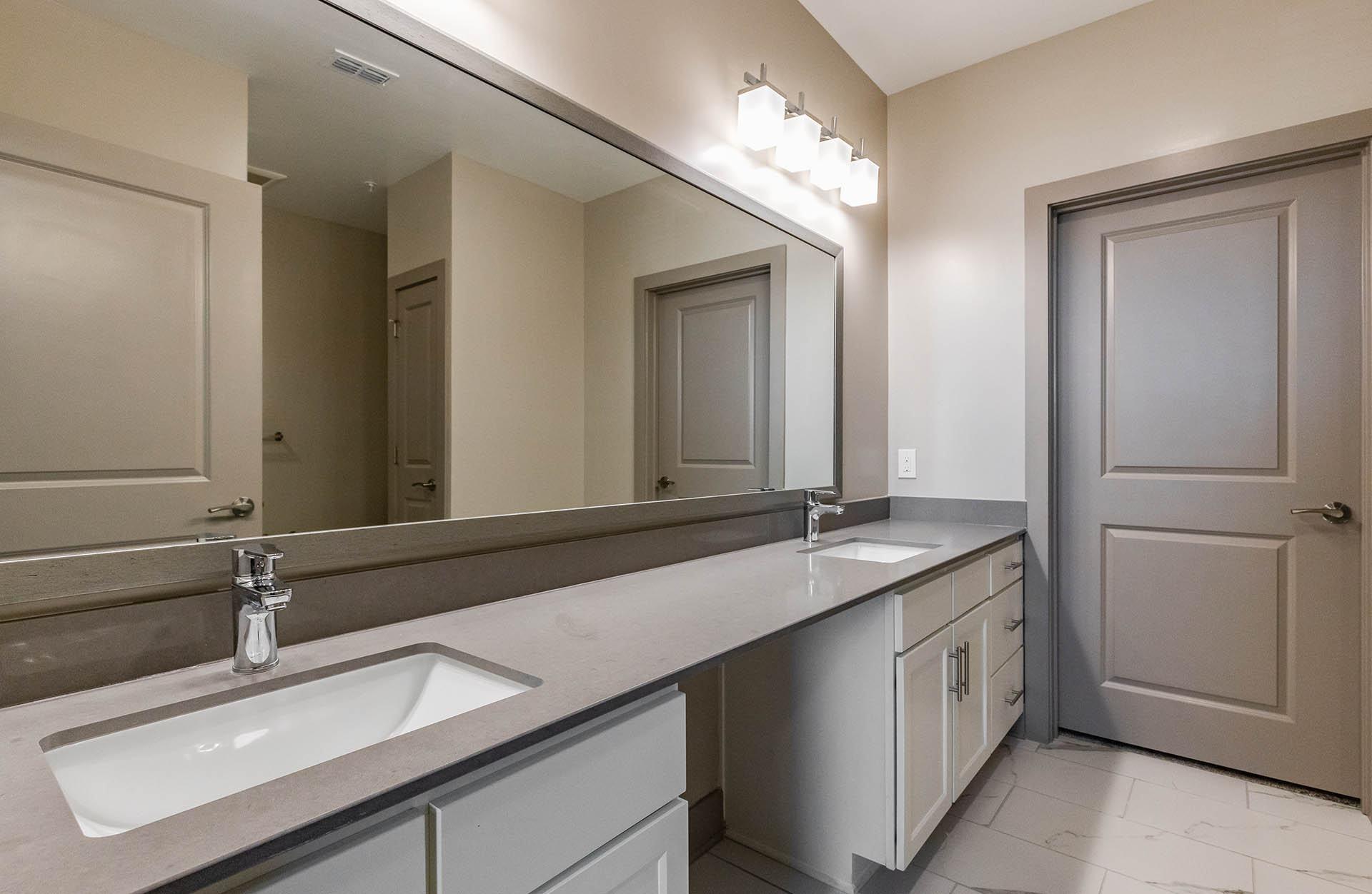 A bathroom with a sink, mirror, and lighting fixture.
