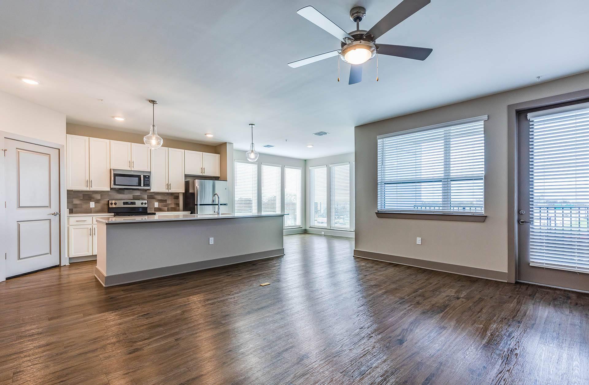 A spacious kitchen with a ceiling fan and wooden floors.