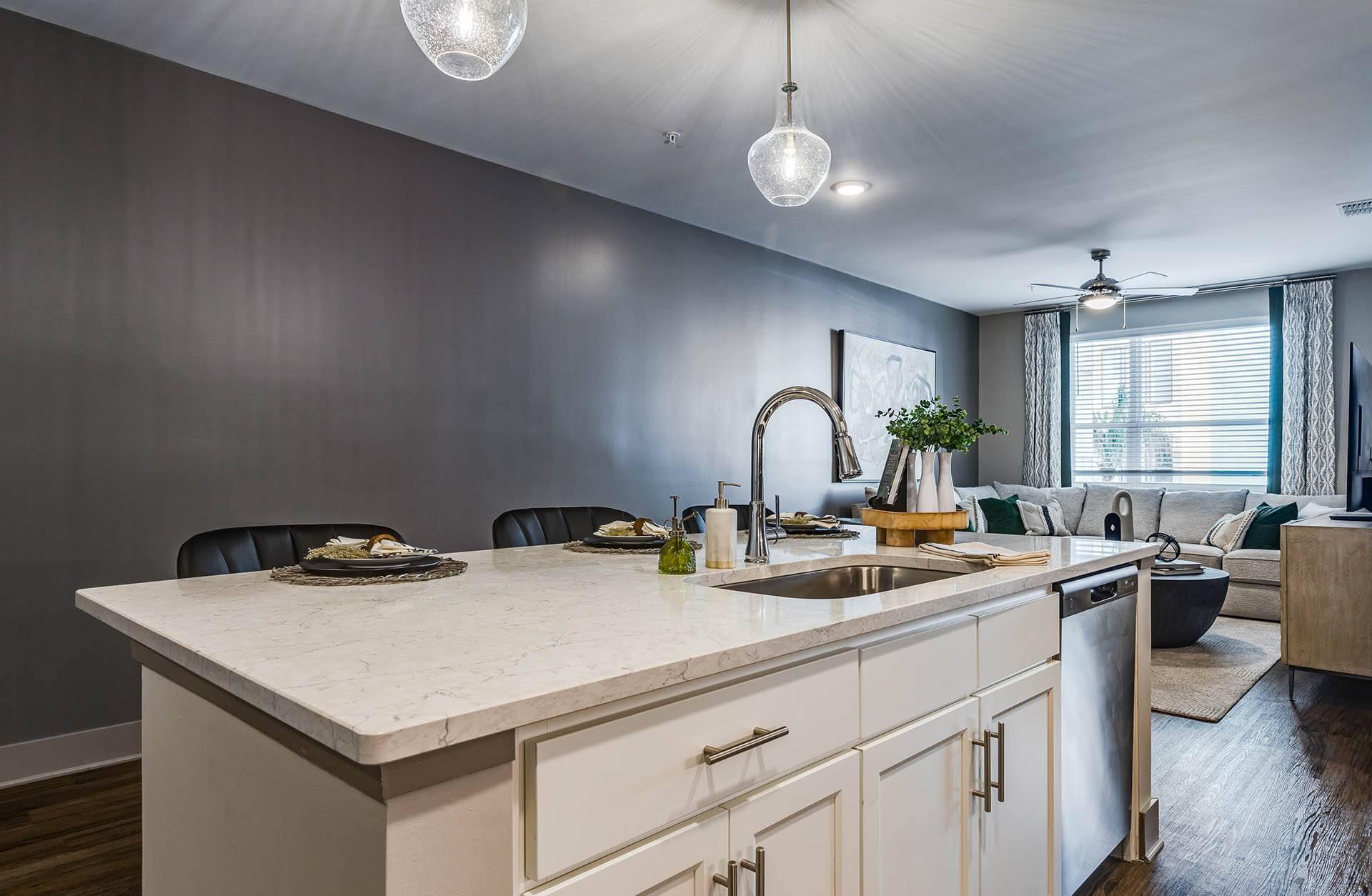 A modern kitchen with a marble countertop and white cabinets.