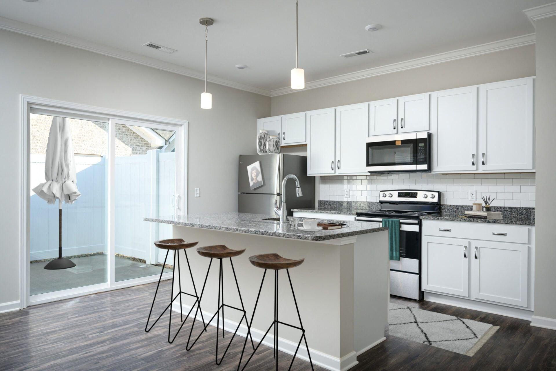 a kitchen with white cabinets and a large island with three stools