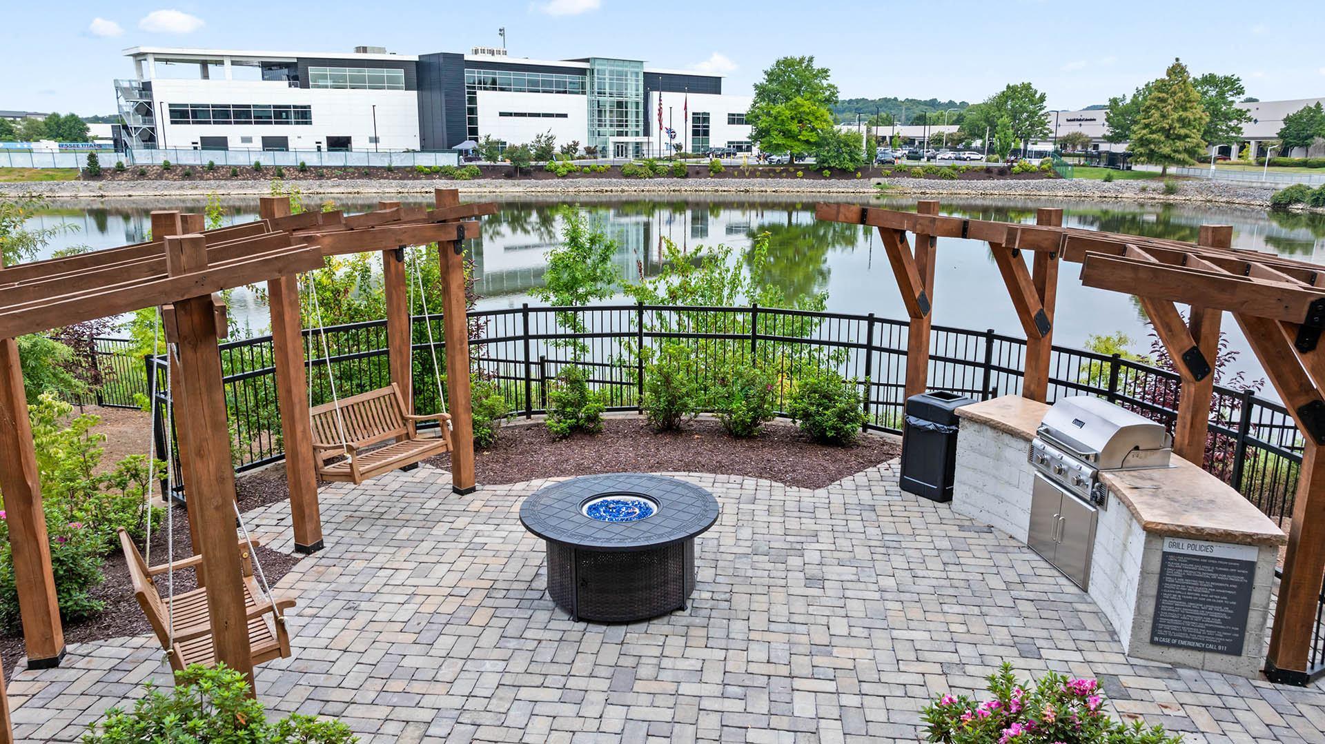 a patio with a fire pit and a lake with buildings in the background