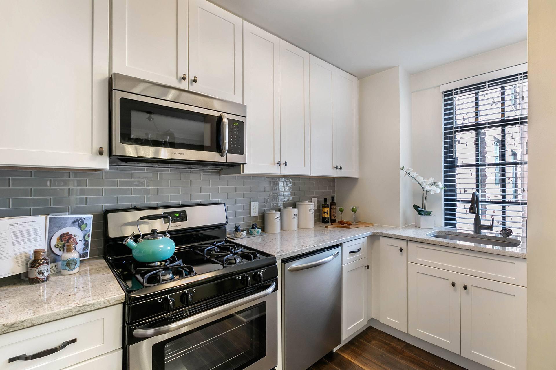A kitchen with white cabinets and a black stove top.