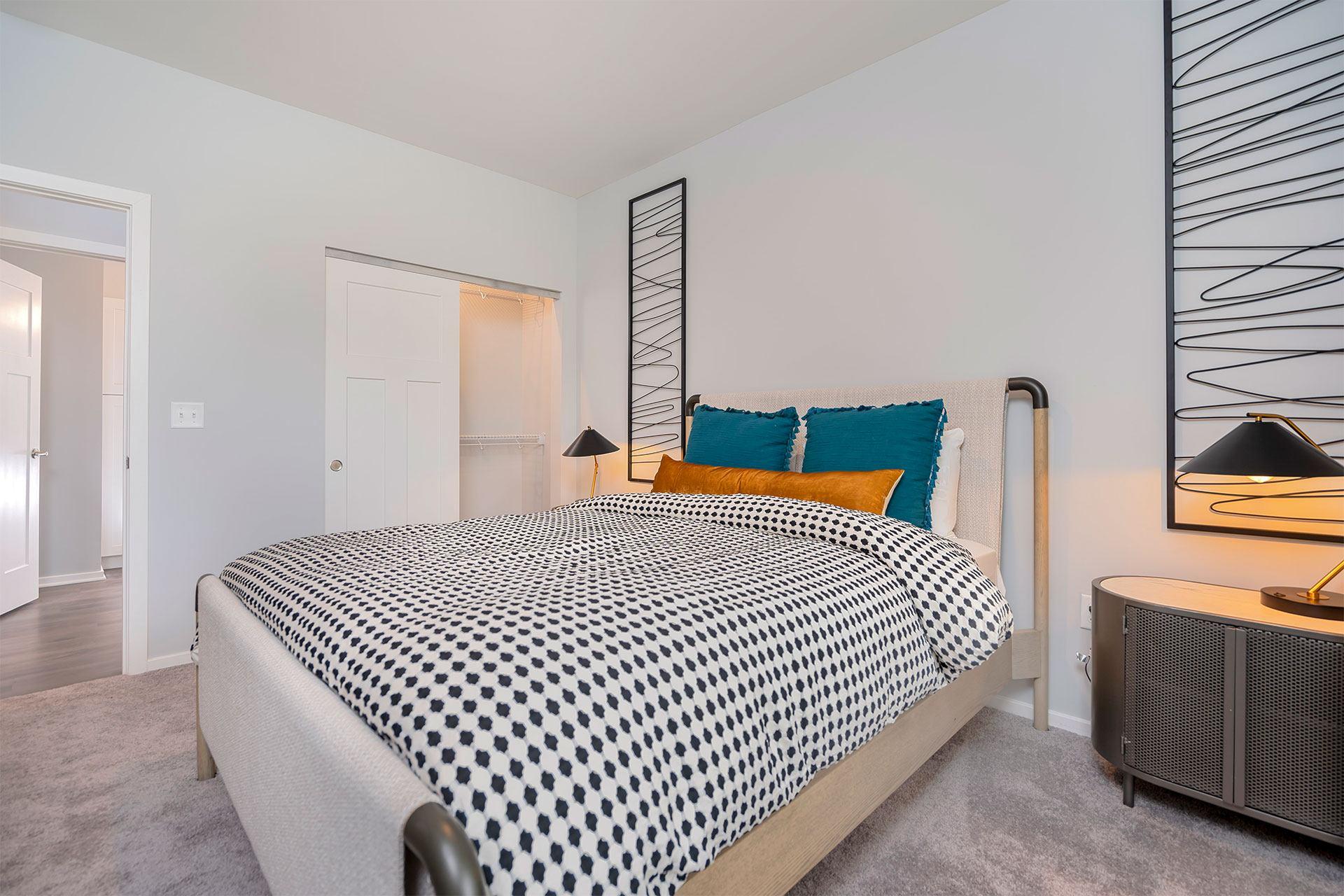 A bedroom with a bed covered in a black and white patterned bedspread.