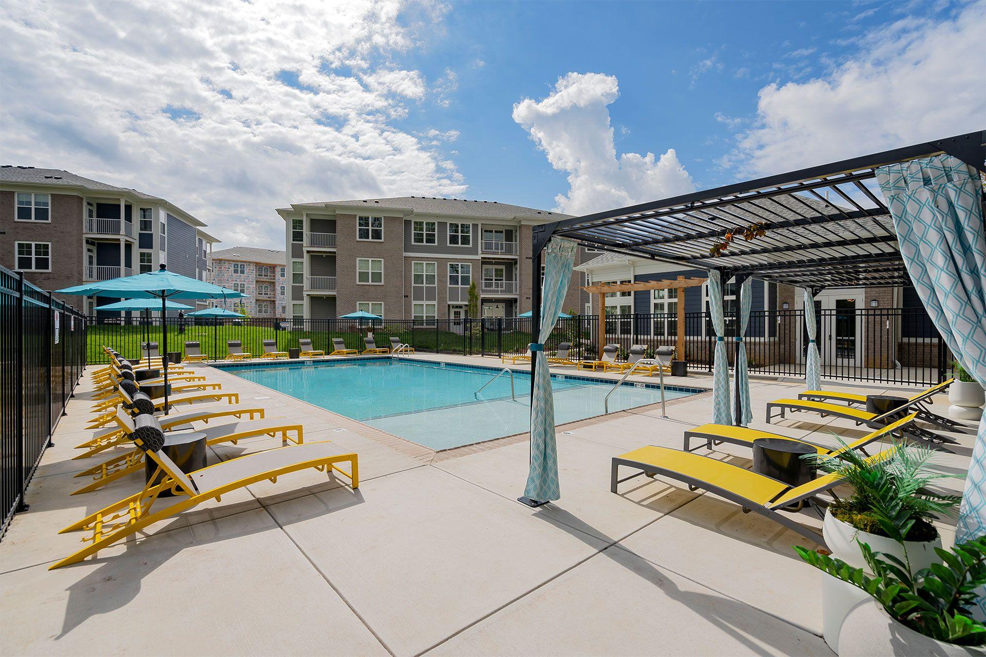 A pool area with sun loungers and umbrellas.