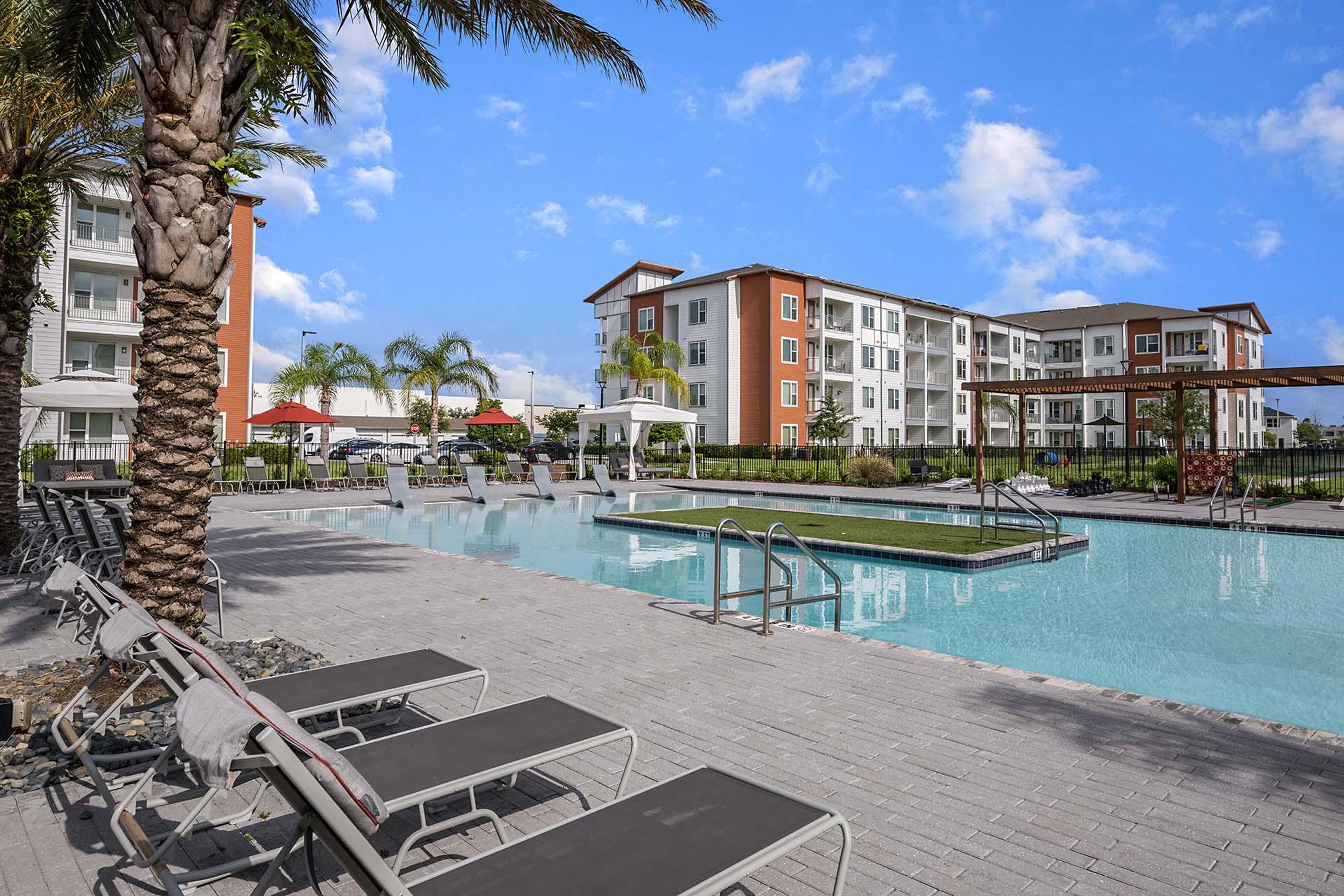 A pool area with sun loungers and a palm tree.