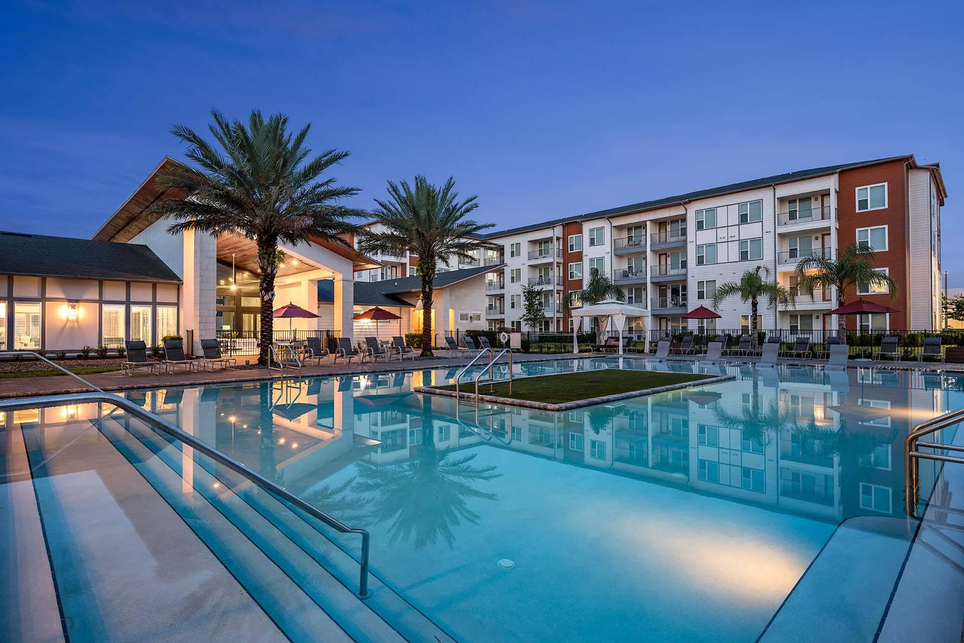 A large swimming pool in front of a multi-story apartment building.