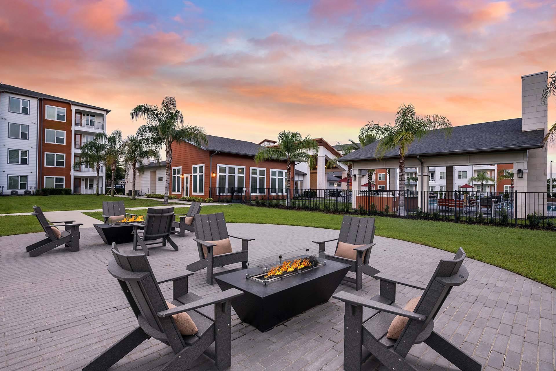 A fire pit surrounded by chairs in a courtyard.