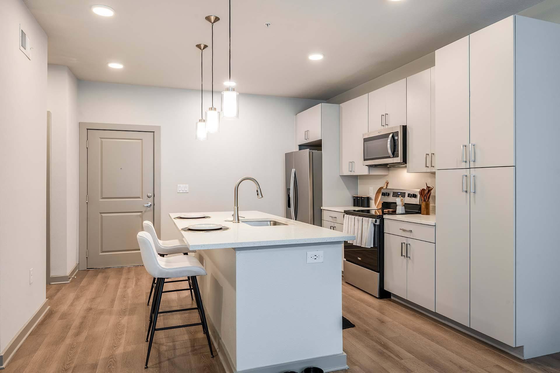 A kitchen with a white island and white chairs.