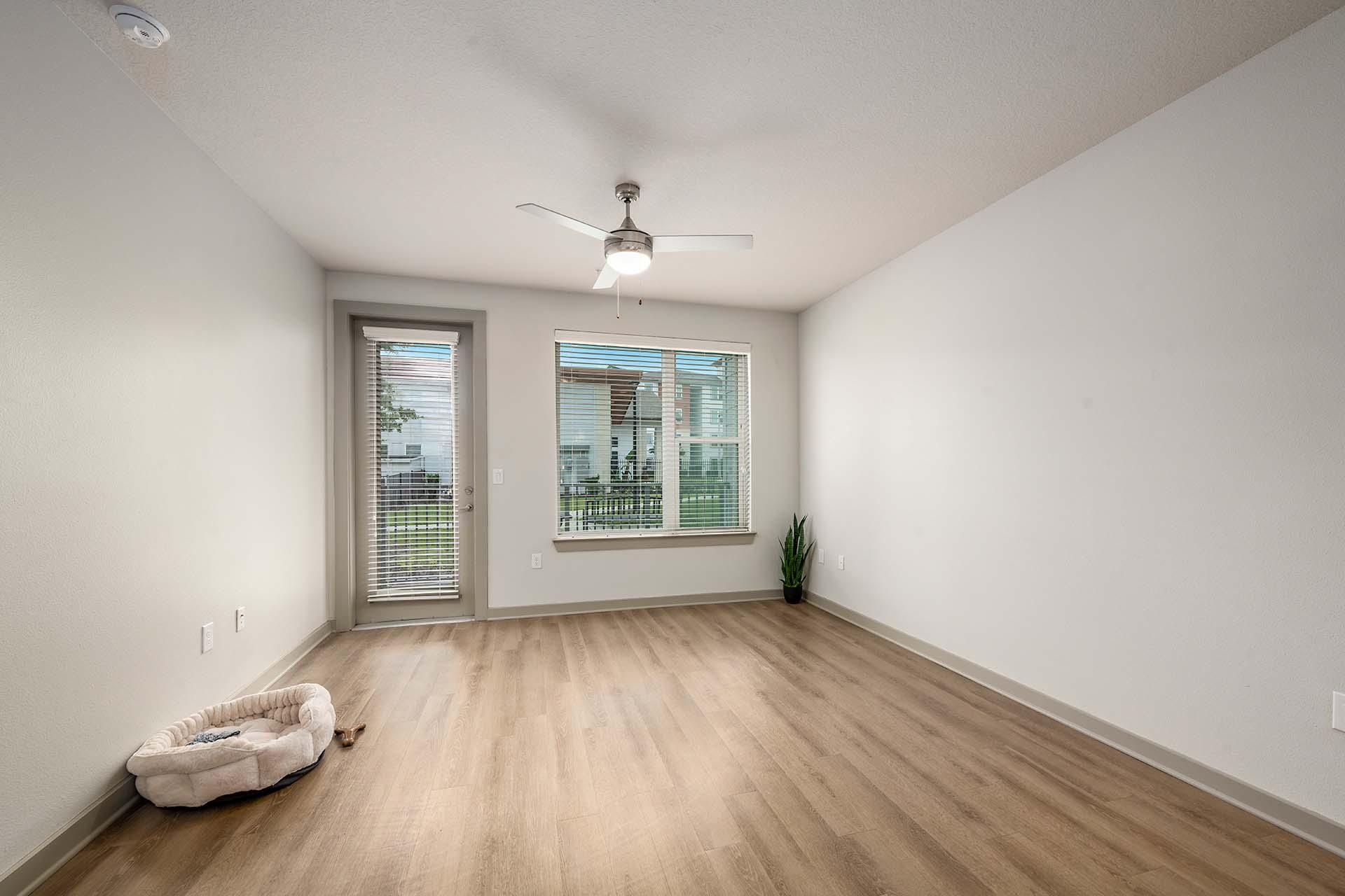 A room with a ceiling fan and a window with a view of a cityscape.