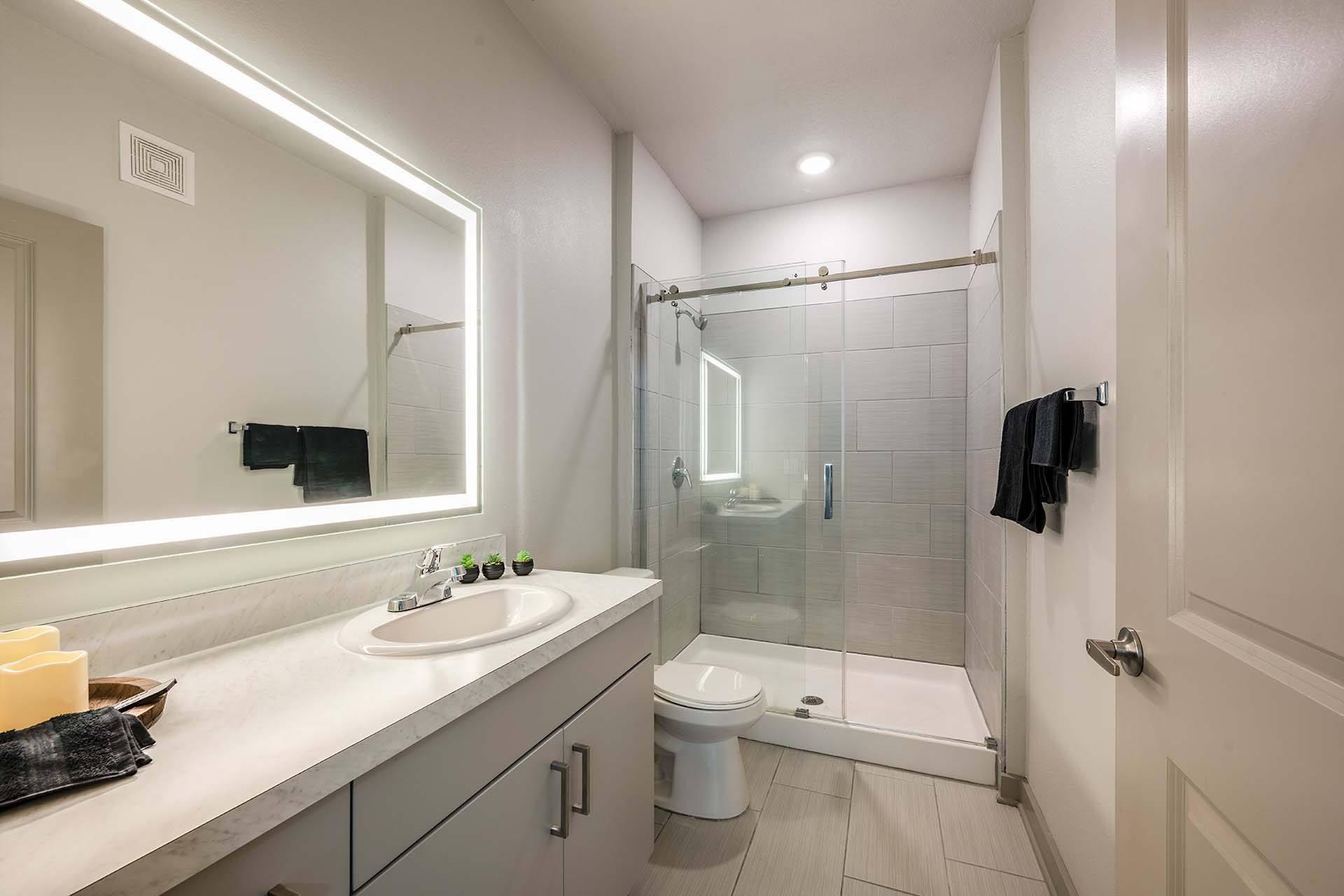A bathroom with a sink, mirror, and shower.