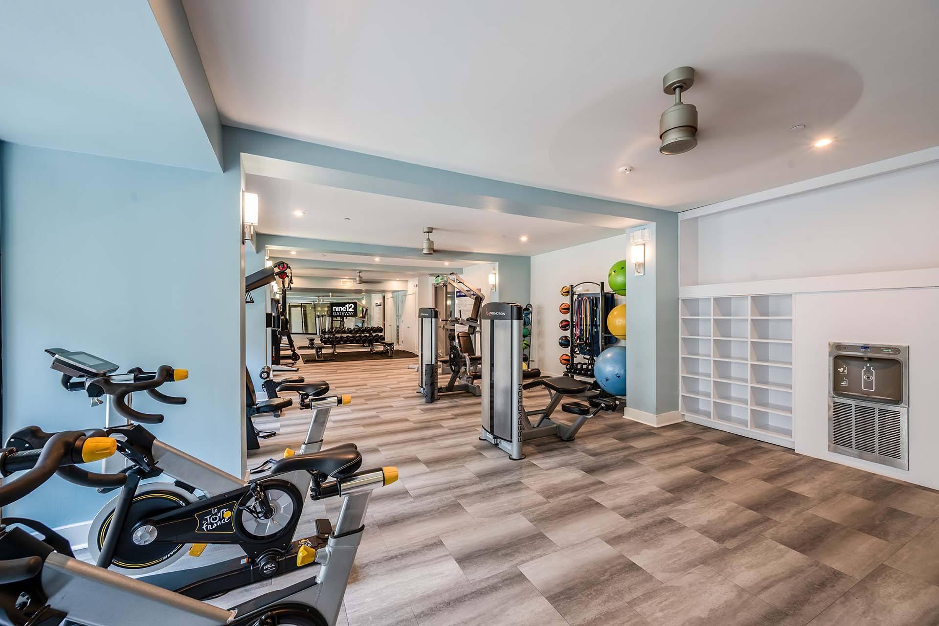 A gym with exercise equipment and a row of stationary bikes.