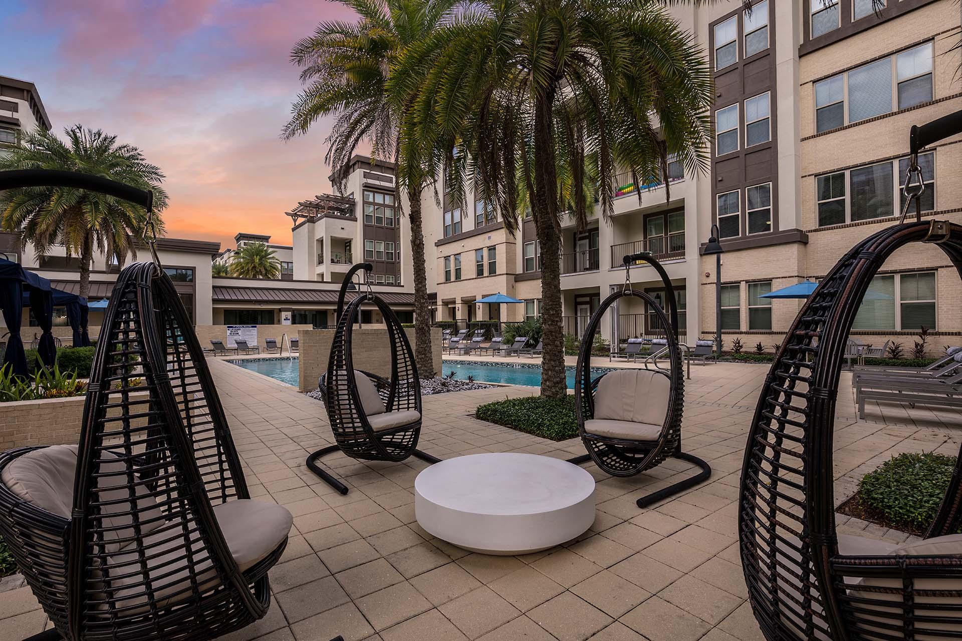 A patio with chairs and a table is surrounded by buildings.