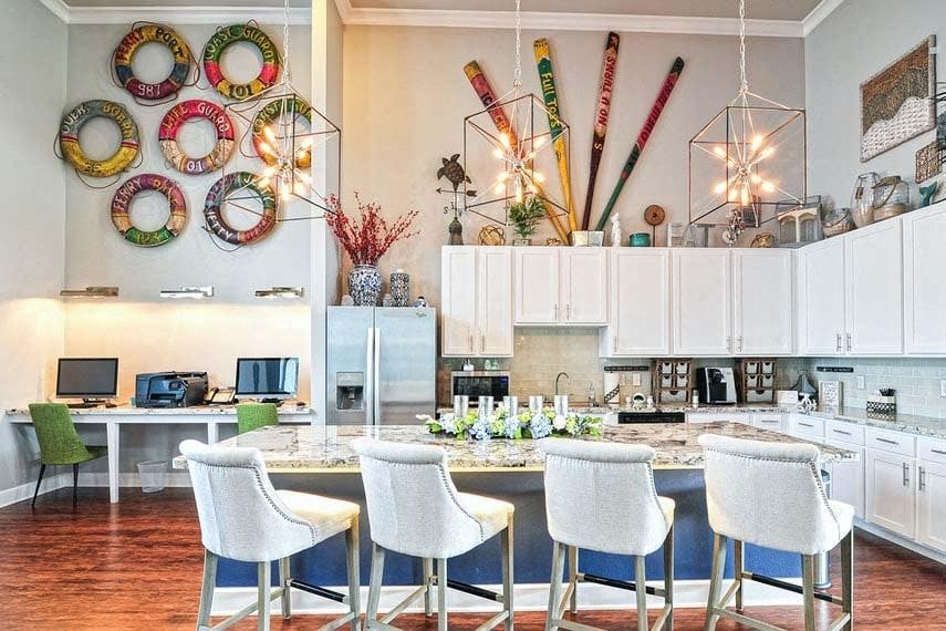 A kitchen with a table and chairs in front of a counter with a laptop on it.