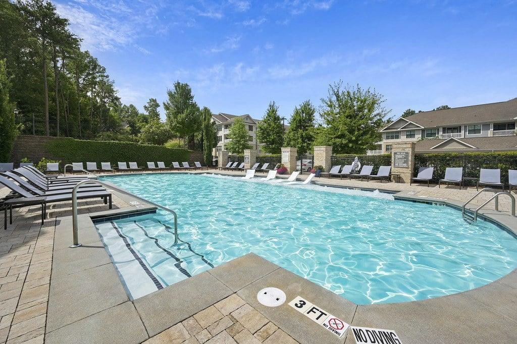 a resort style pool with lounge chairs and a building in the background