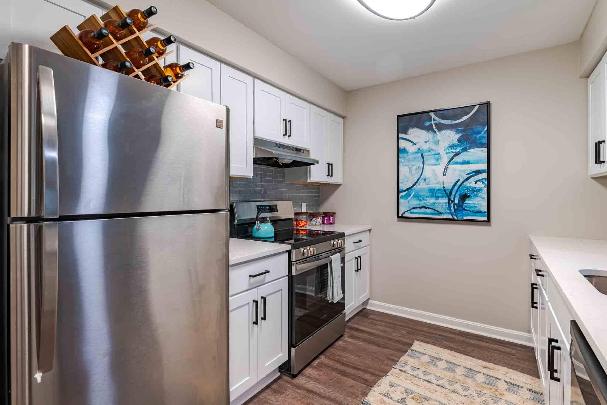 A modern kitchen with a stainless steel refrigerator and white cabinets.