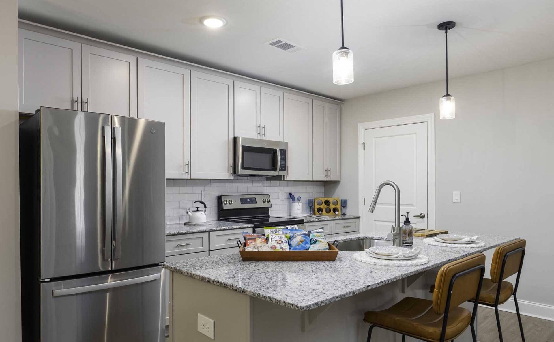 A modern kitchen with a stainless steel refrigerator and a granite countertop.