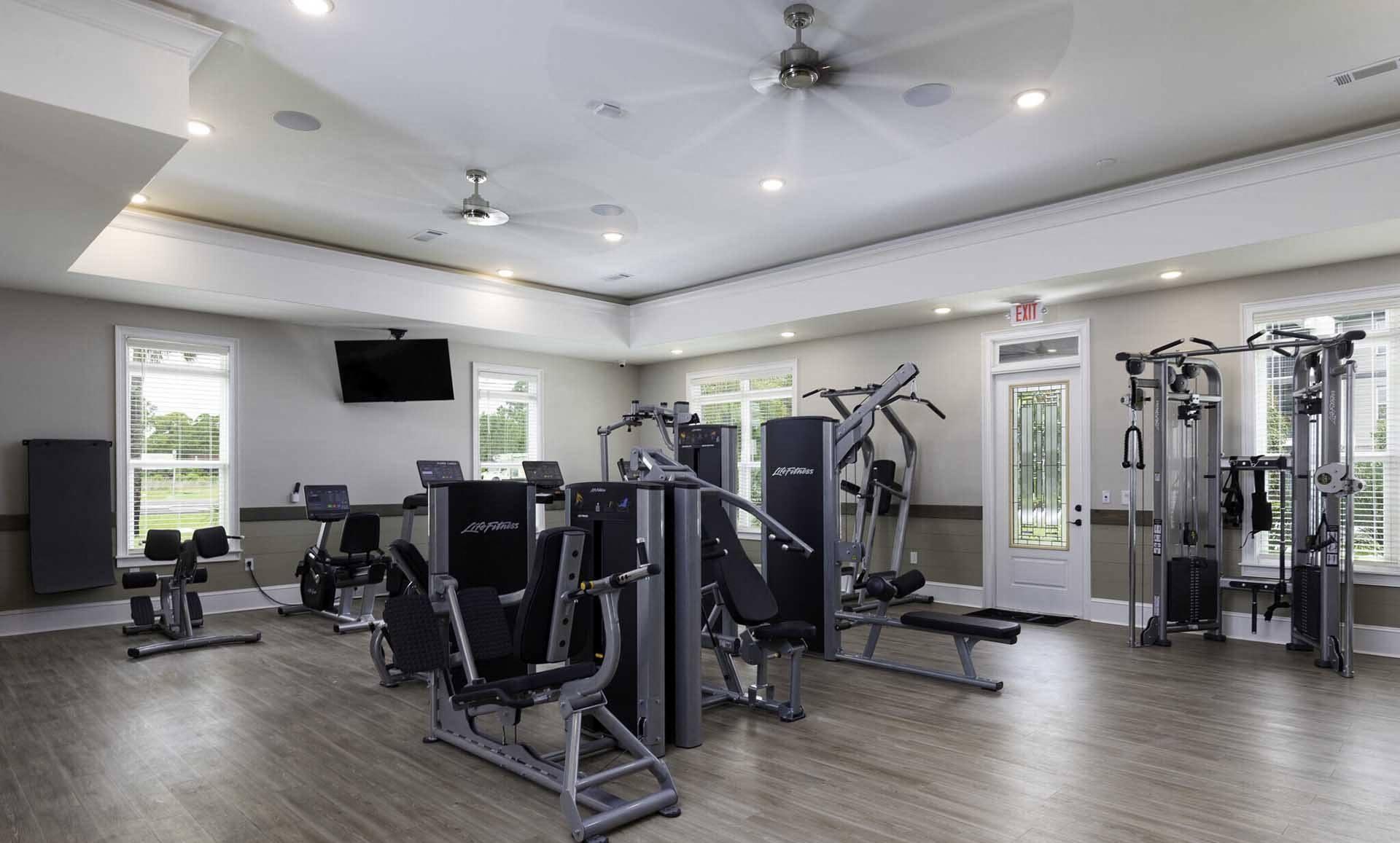 A spacious gym with a variety of equipment and a flat screen TV mounted on the wall.