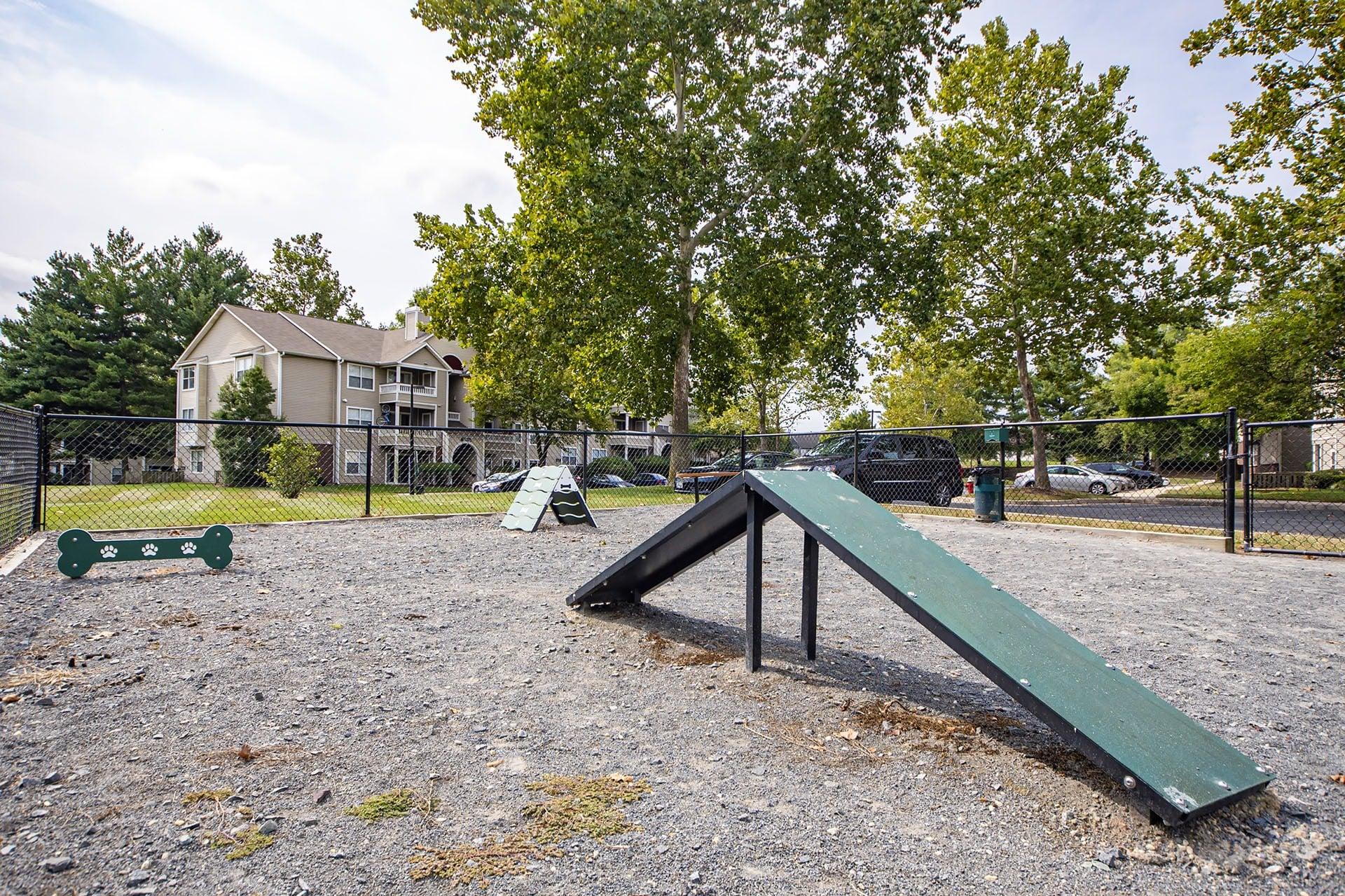 A playground with a green slide and a black fence.