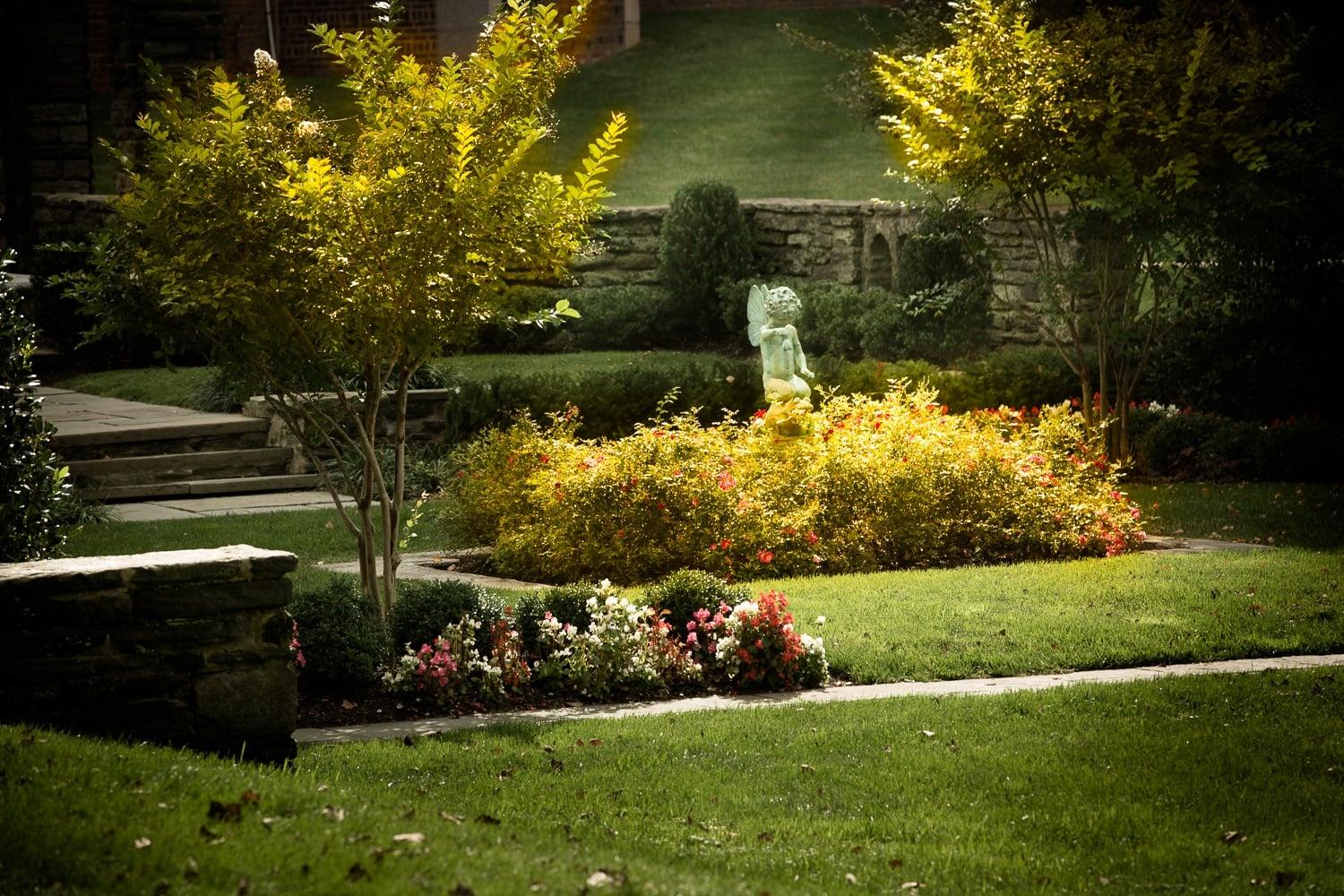 A garden with a statue and a yellow tree.