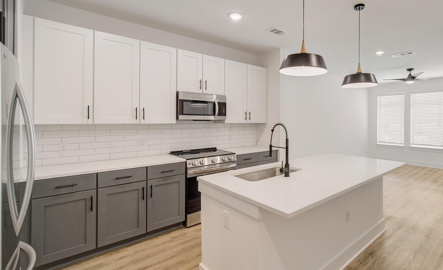A modern kitchen with white and grey cabinets and a large island.