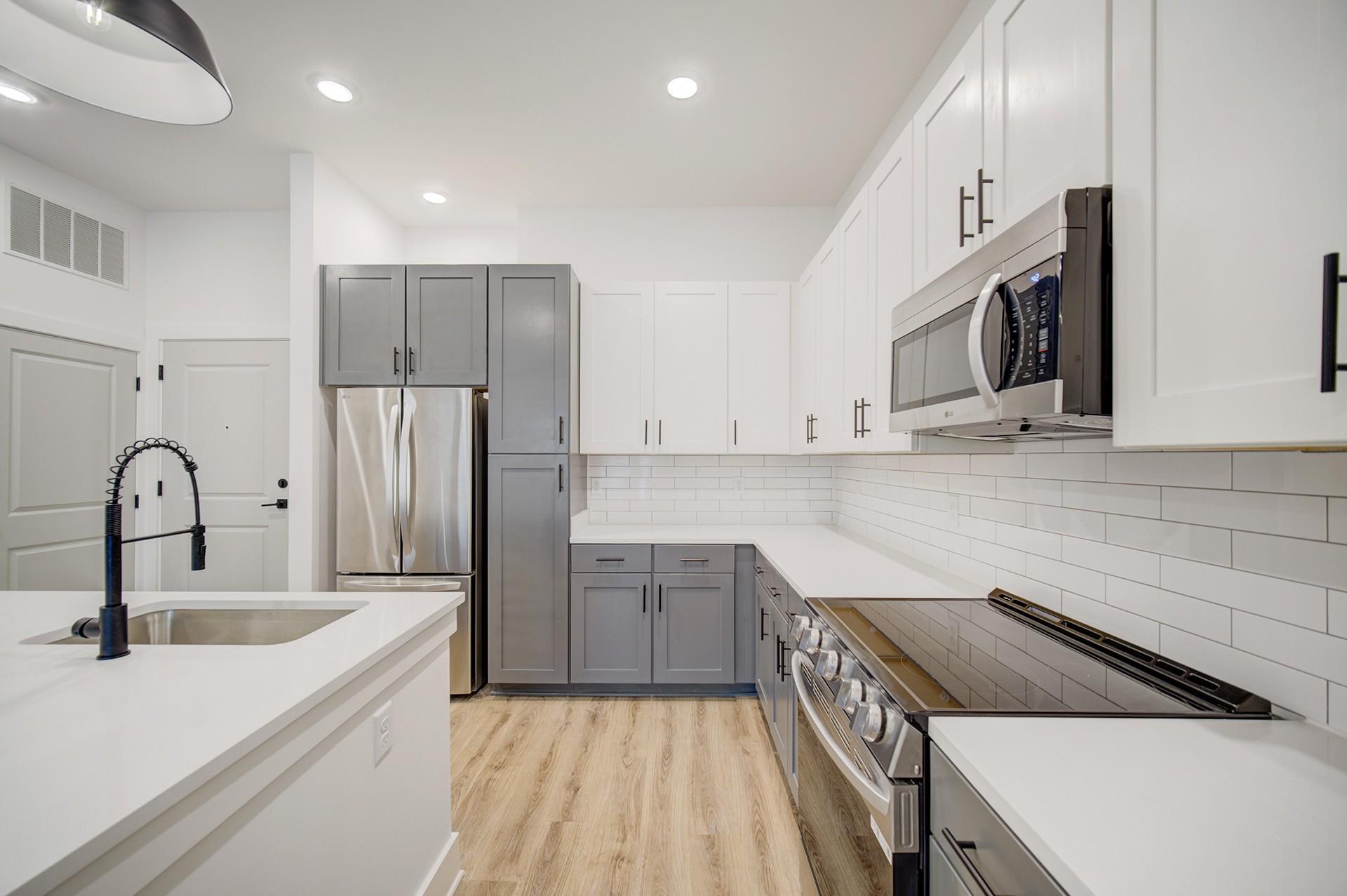 A modern kitchen with white cabinets and a wooden floor.