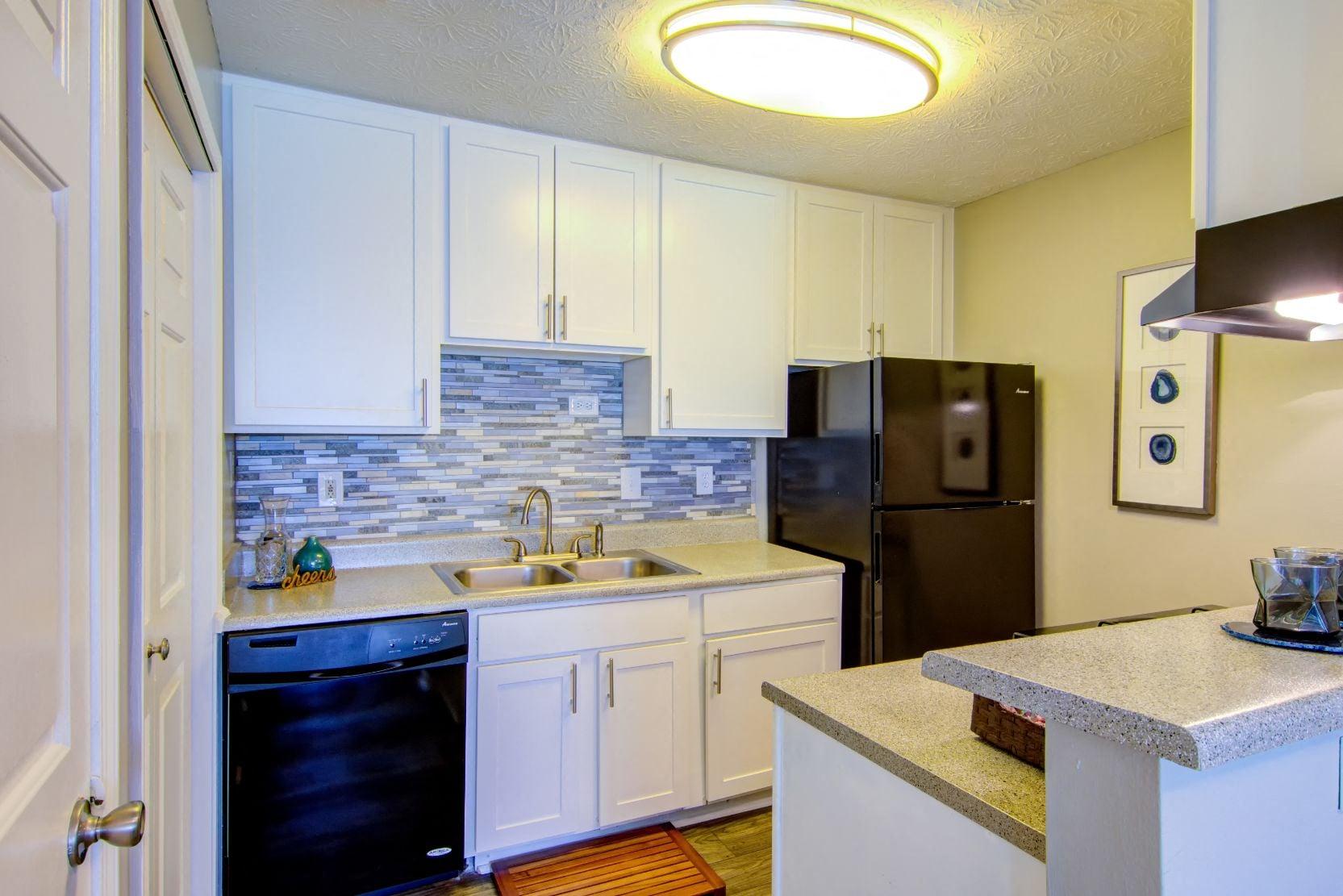 a kitchen with white cabinets and black appliances