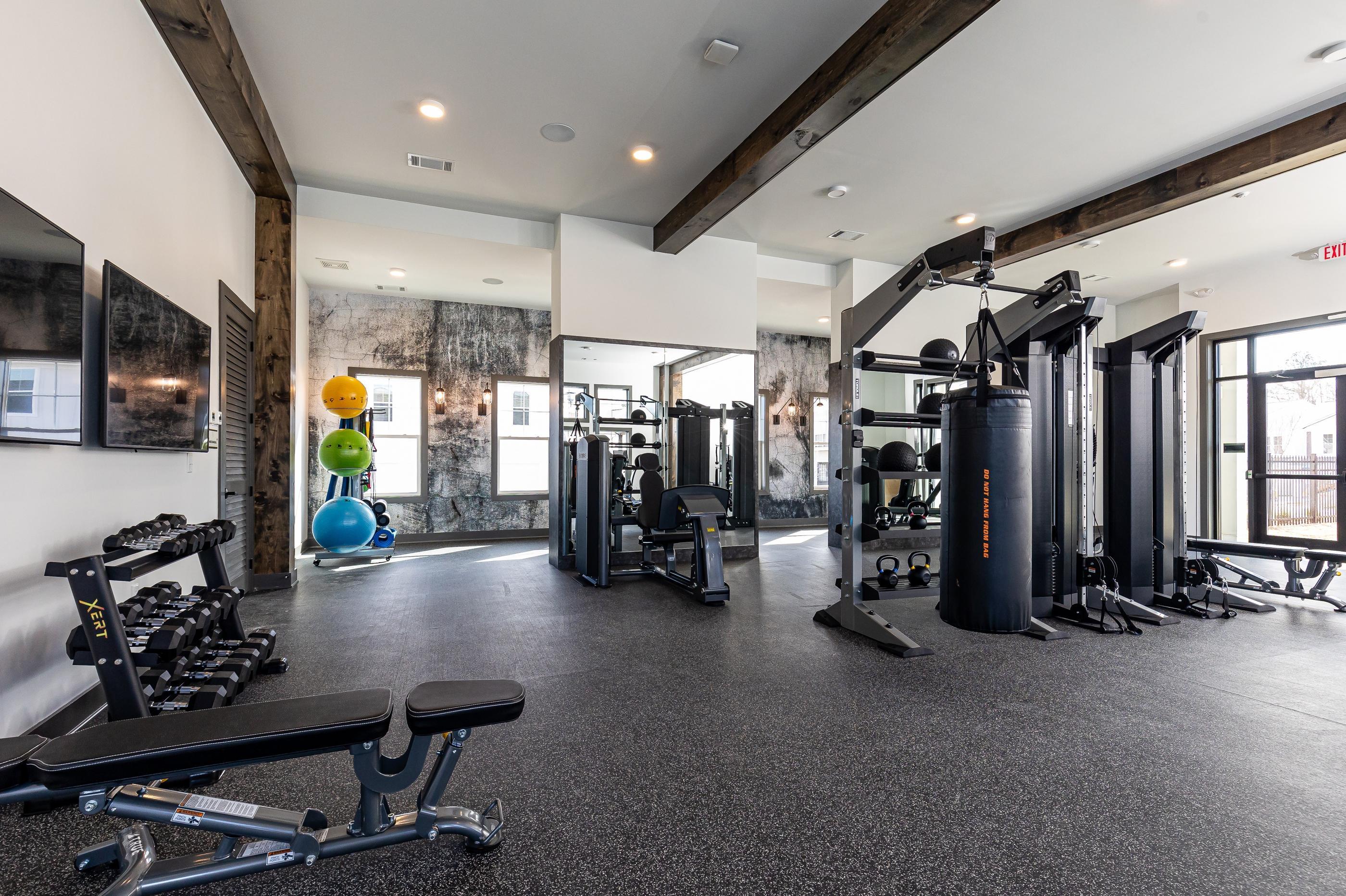 A gym with a variety of equipment including a squat rack, dumbbells, and a bench.